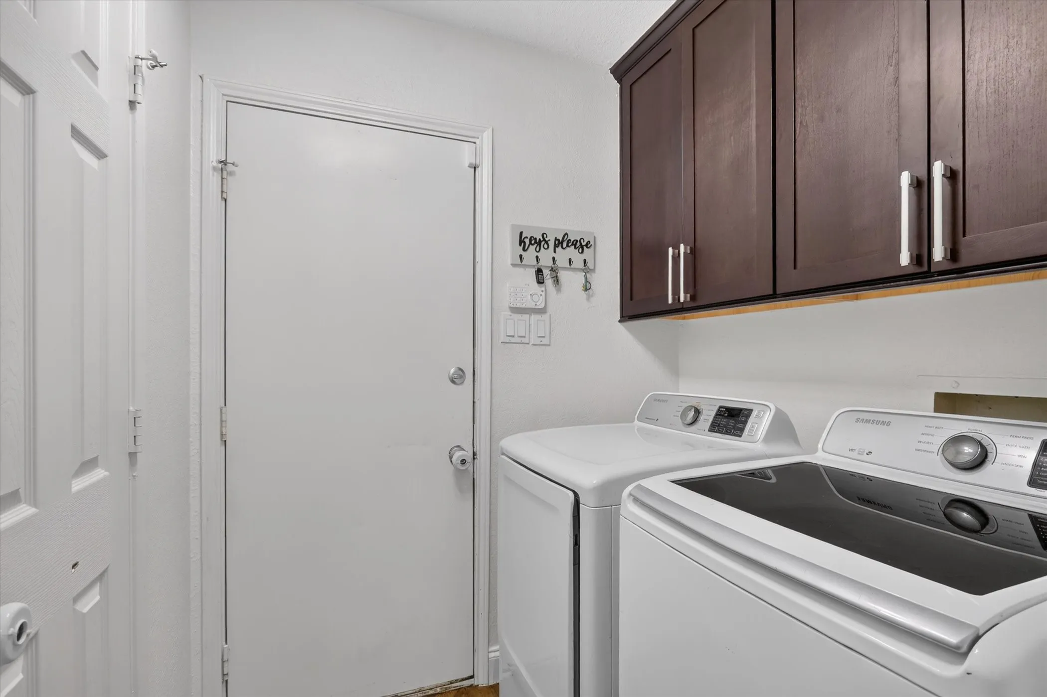 Dark wood-finish cabinetry with silver-tone hardware, white washer and dryer, and white interior doors
