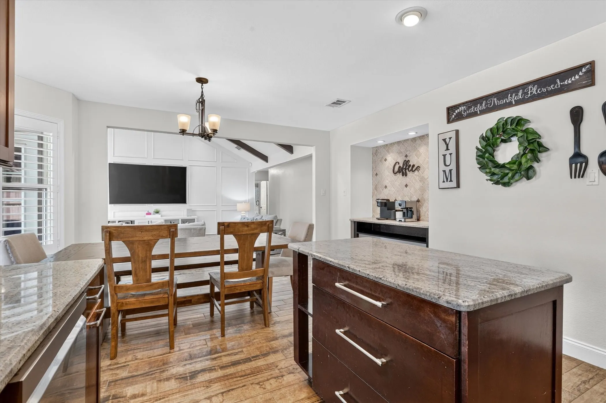 Kitchen featuring a center island with a light-toned countertop, wood-finish tile flooring, and a dedicated beverage station with tiled backsplash