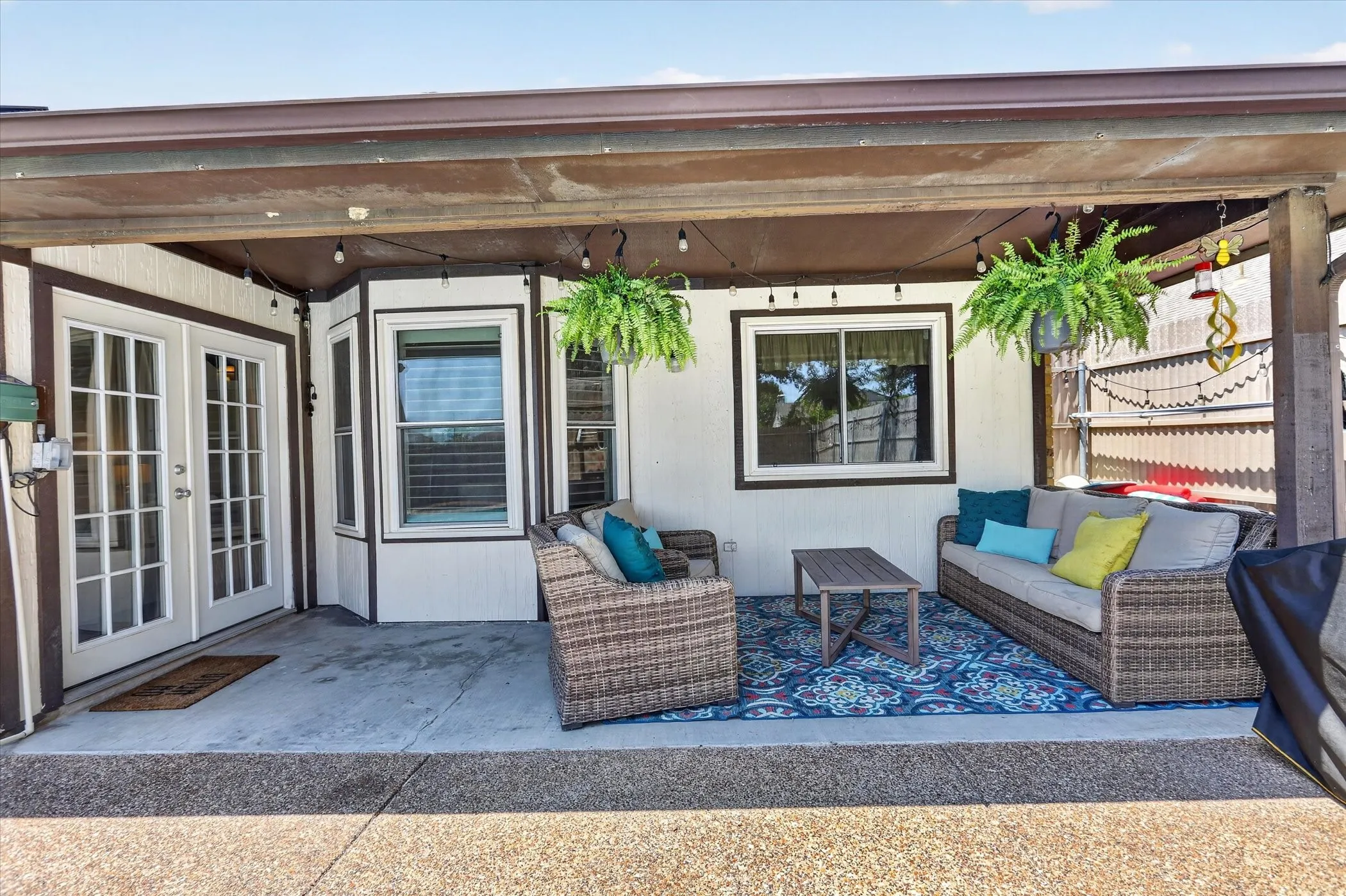 Covered patio with concrete flooring, white French doors, and multiple windows