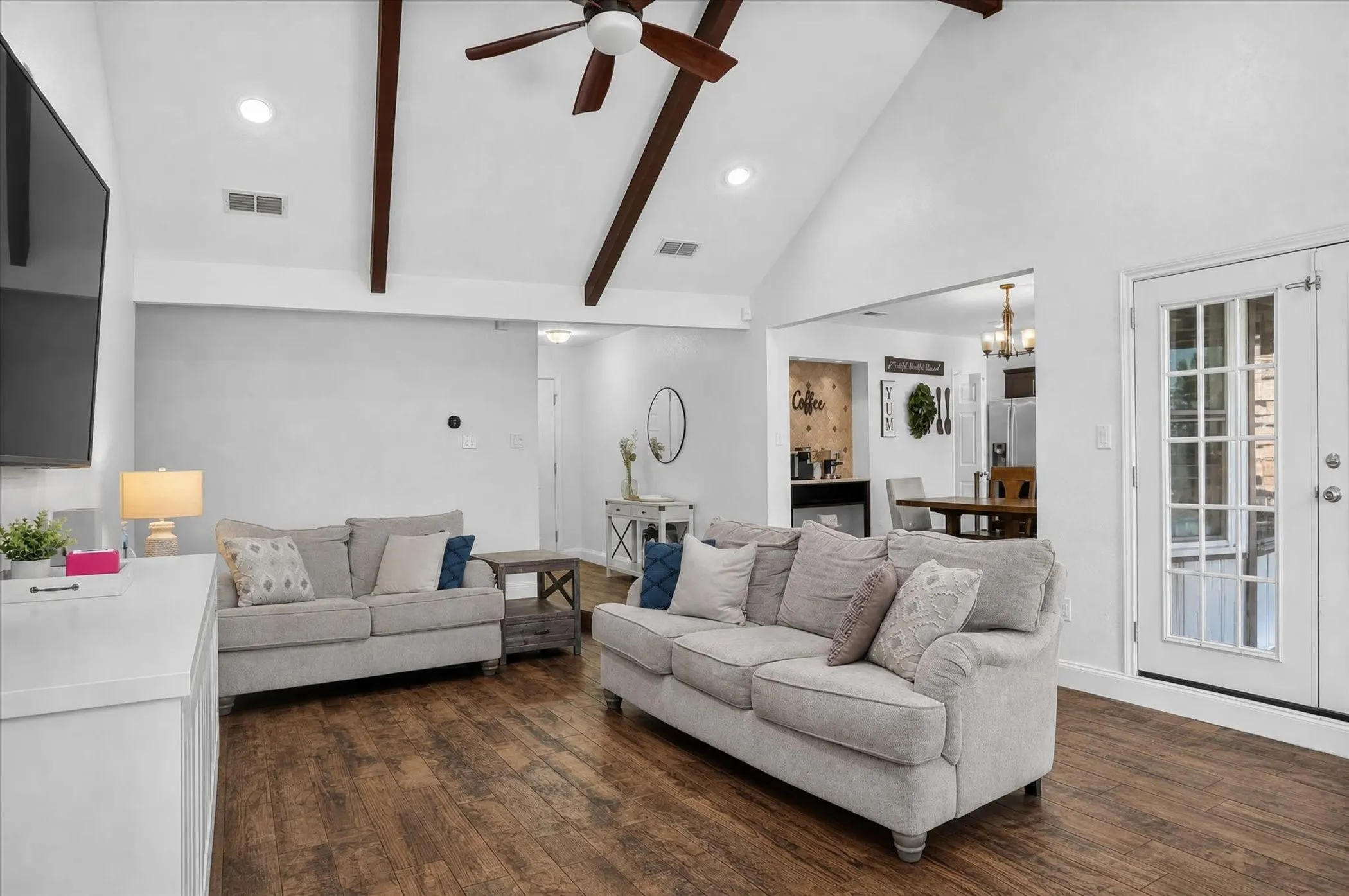 Vaulted ceiling with exposed wood beams and ceiling fan, wood-finish tile flooring, recessed lighting, and French doors