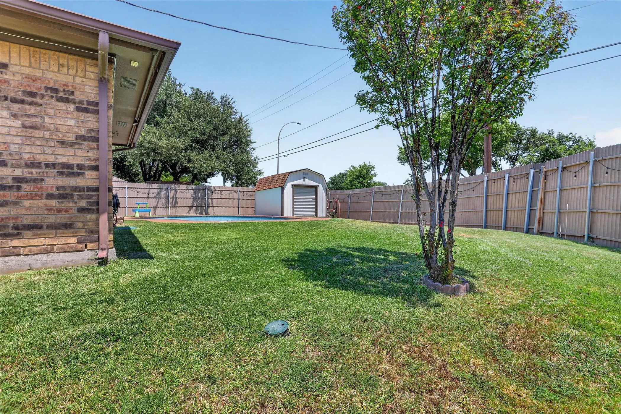 Brick exterior, fenced yard, in-ground pool, detached storage shed, and mature tree