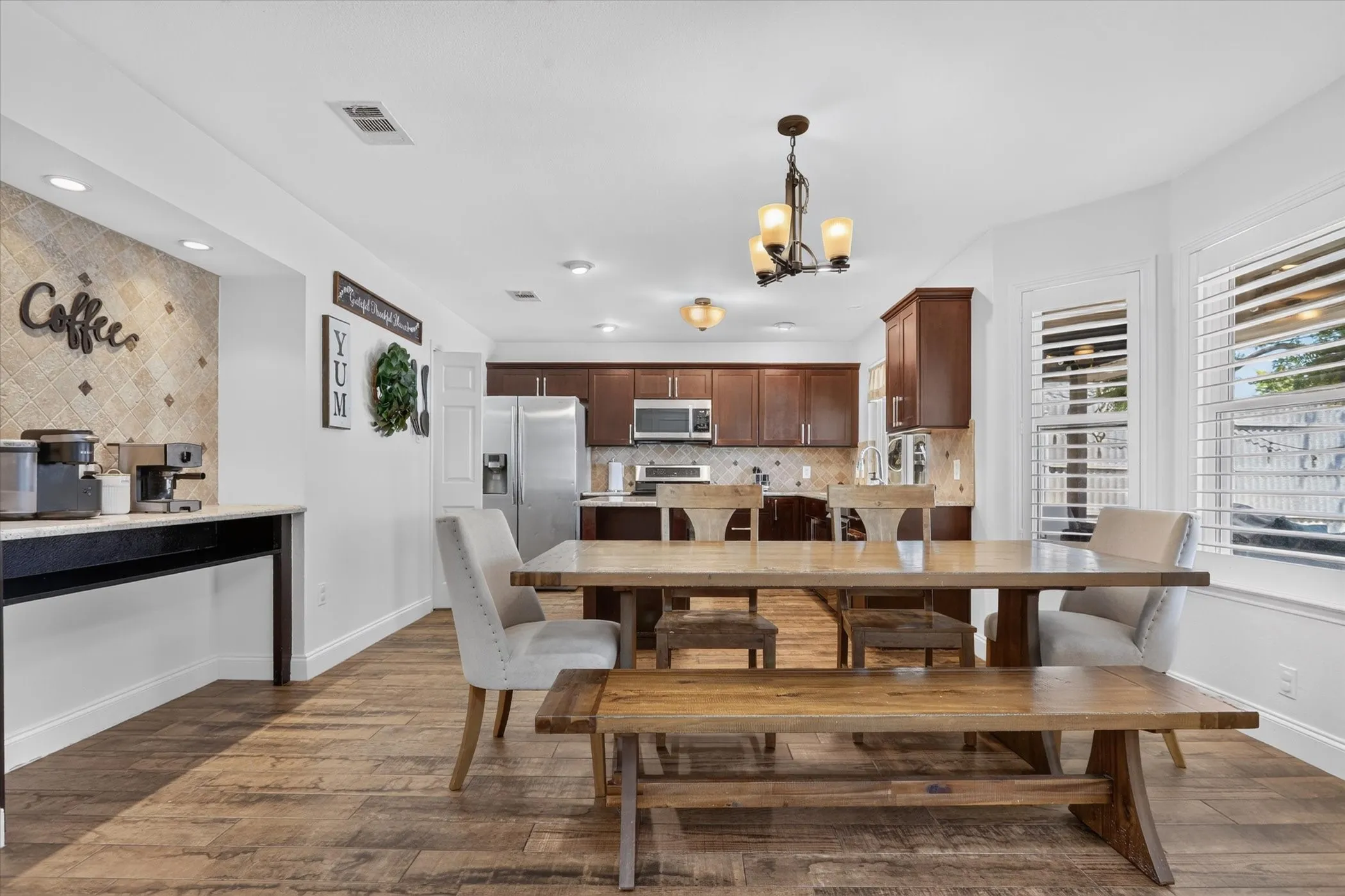 Open-concept living area featuring wood-finish tile flooring, recessed lighting, and a bay window with plantation shutters