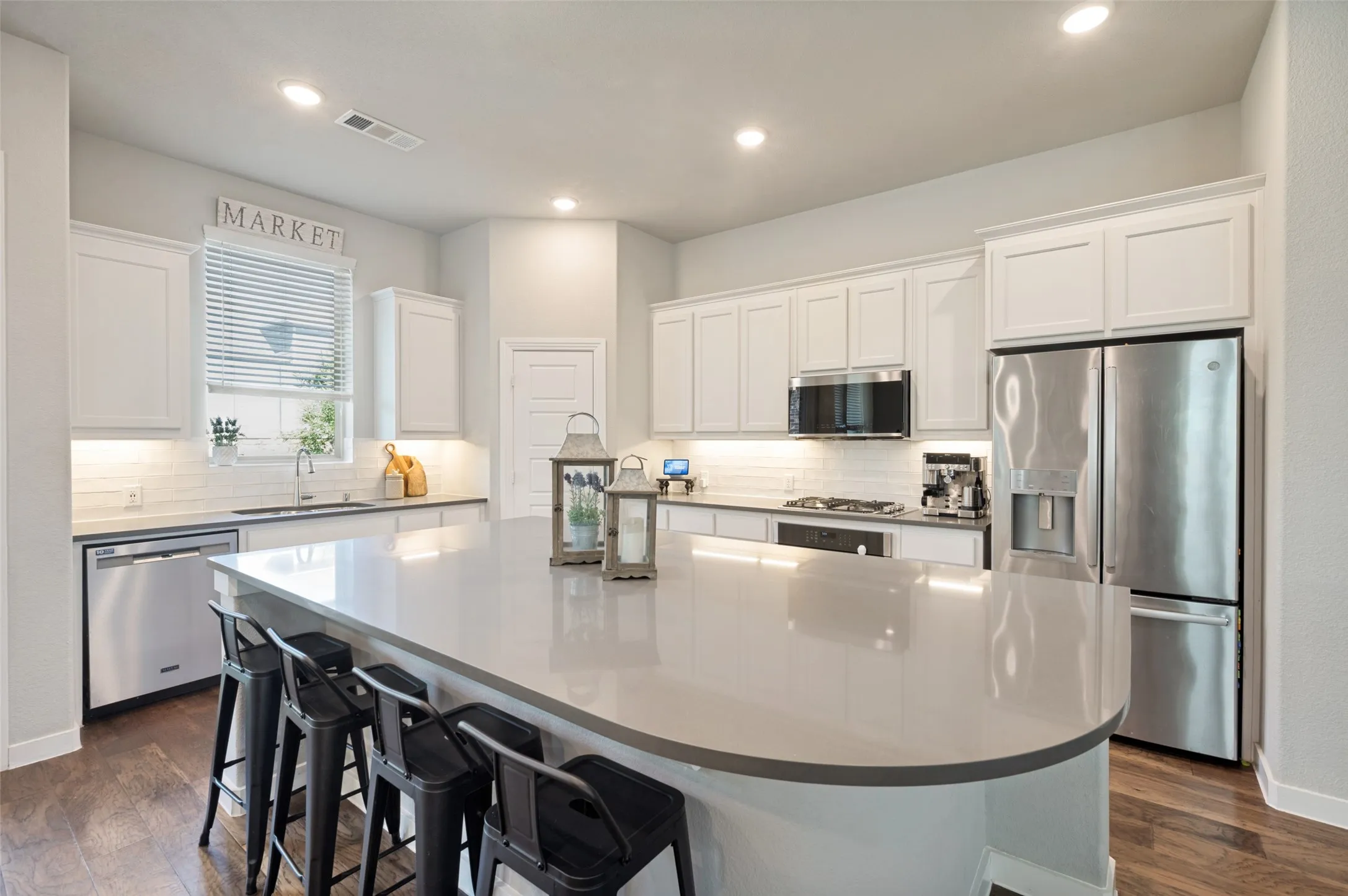 The well-appointed kitchen offers a large island with seating for four, 4-burner gas cooktop, abundant cabinetry and walk-in pantry.