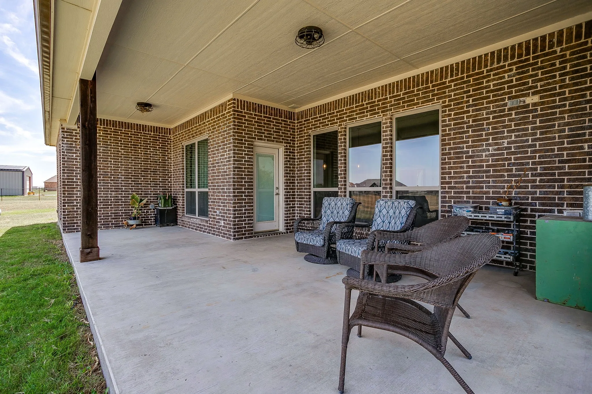 Covered patio with a concrete surface, brick exterior, and multiple windows