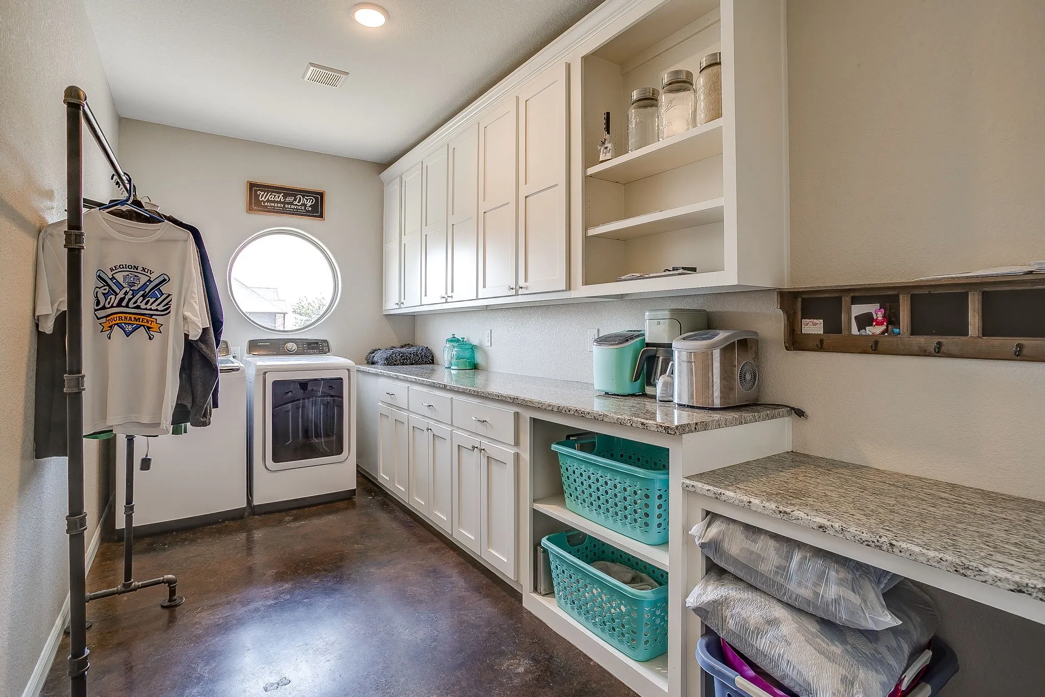 White cabinetry, granite countertops, built-in shelving, circular window, and dark-finish flooring