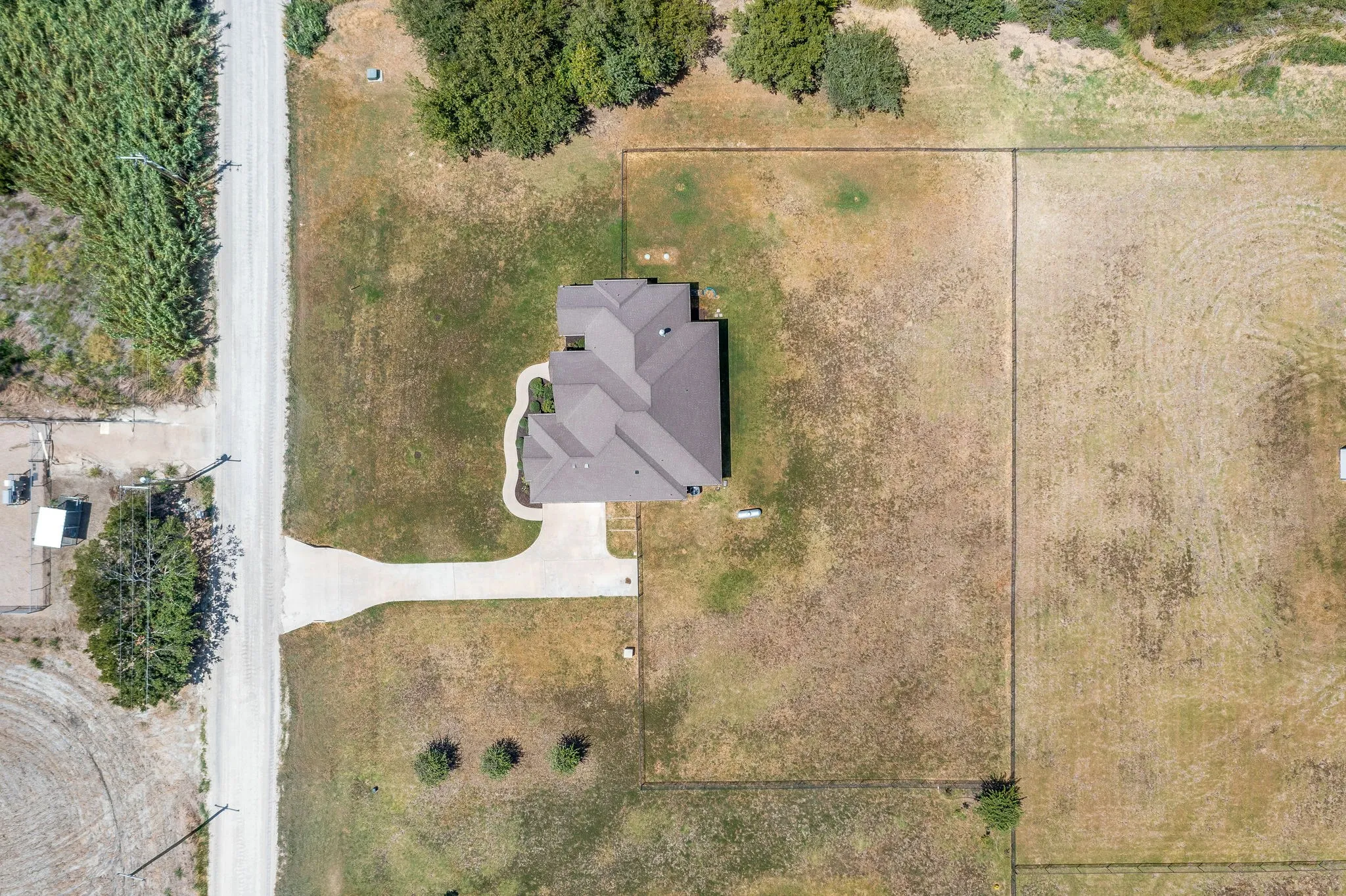 Property featuring a pitched roof, an attached driveway, and a fenced perimeter