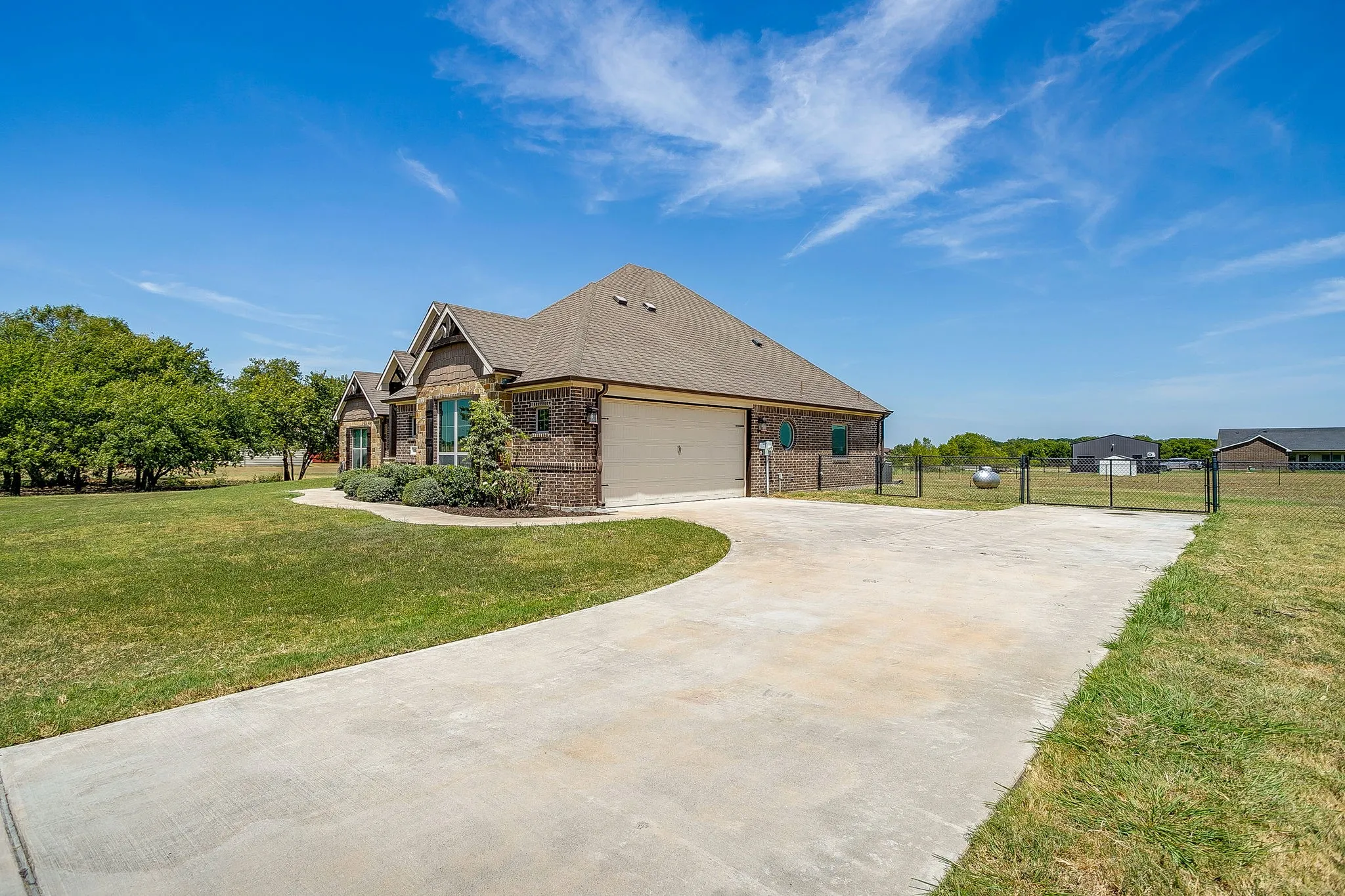 Brick exterior with stone accents, attached garage, concrete driveway, and mature landscaping