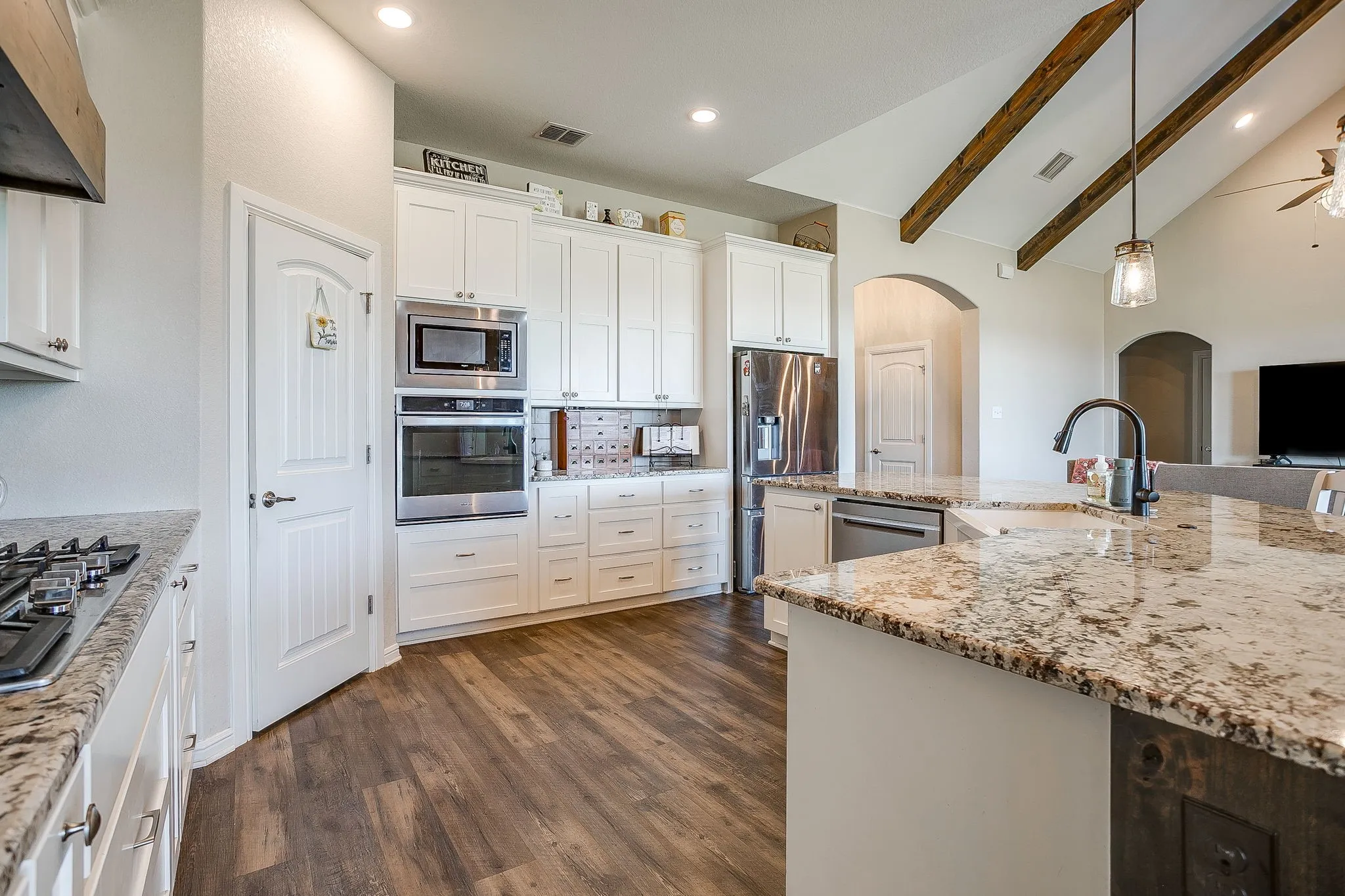 Kitchen featuring wood-finish flooring, white cabinetry, stainless steel appliances, and granite countertops