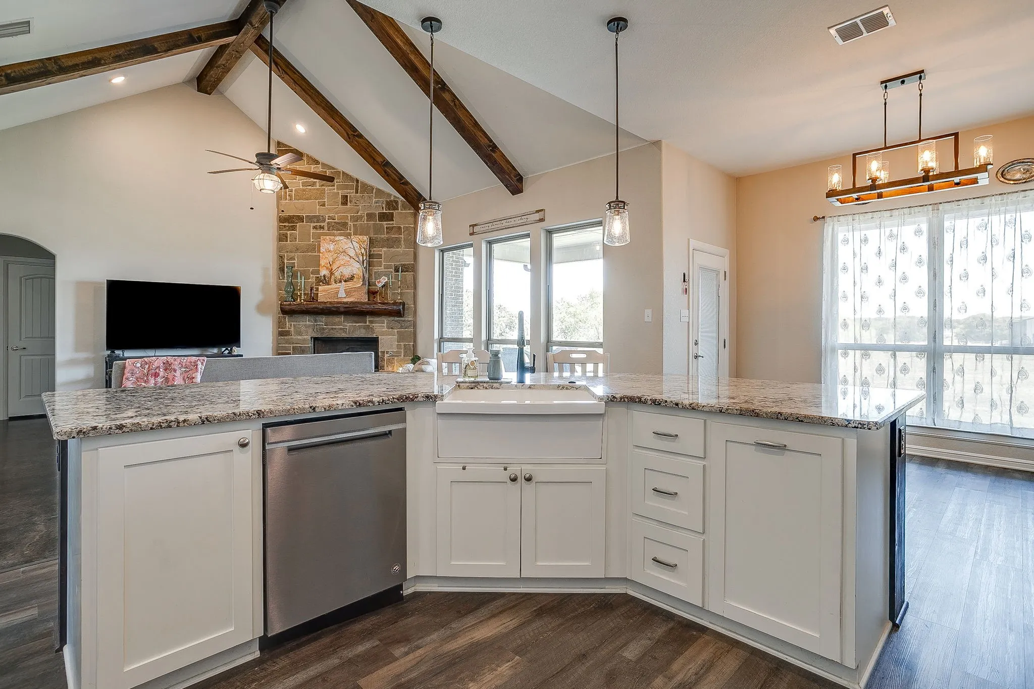 Kitchen island with light-toned granite countertops, white cabinetry, and a farmhouse sink