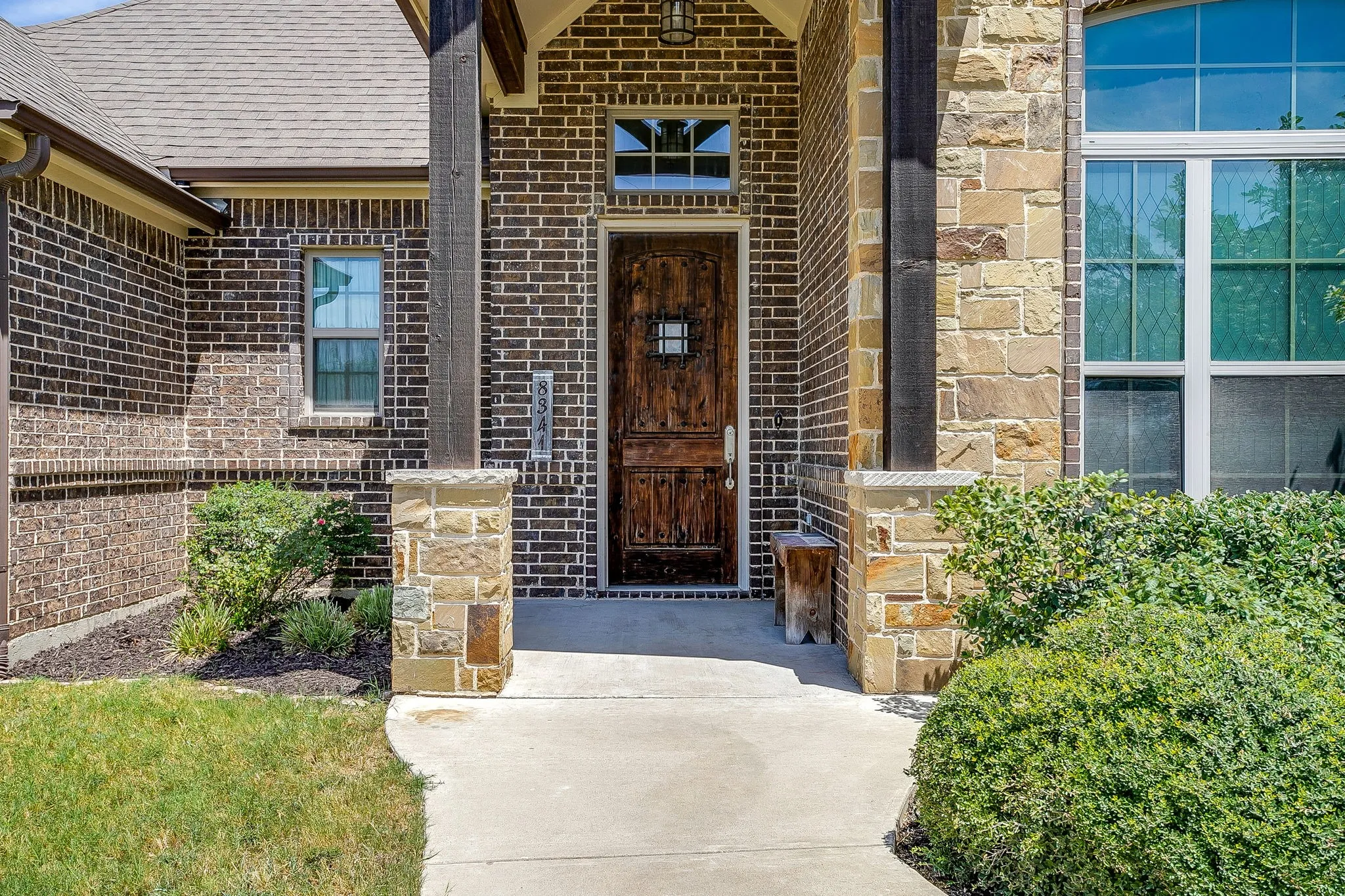 Brick and stone exterior featuring a wood entry door, arched entry, and decorative windows