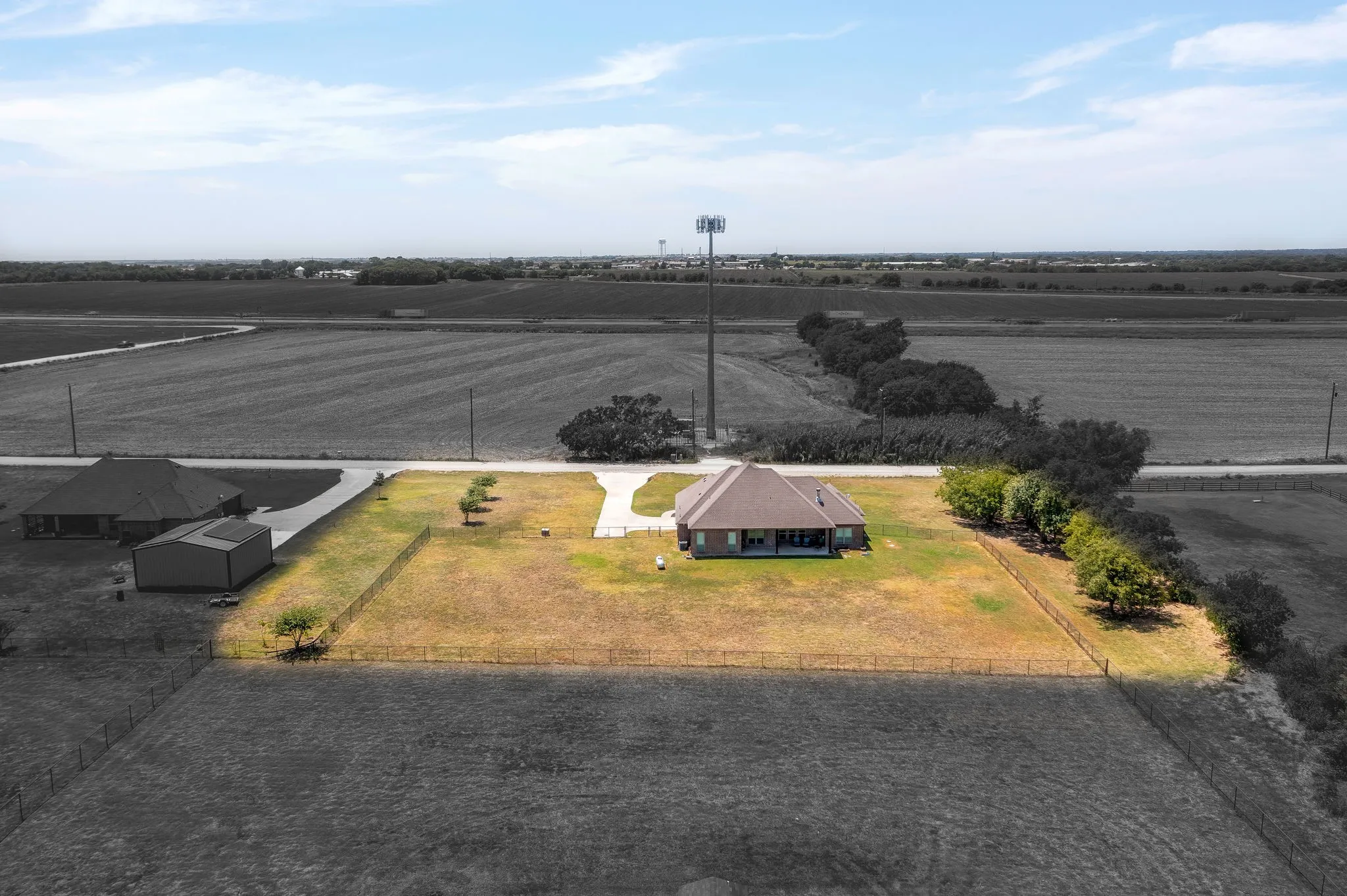 Expansive property featuring a brick exterior home with a covered back patio, fenced yard, and dedicated driveway