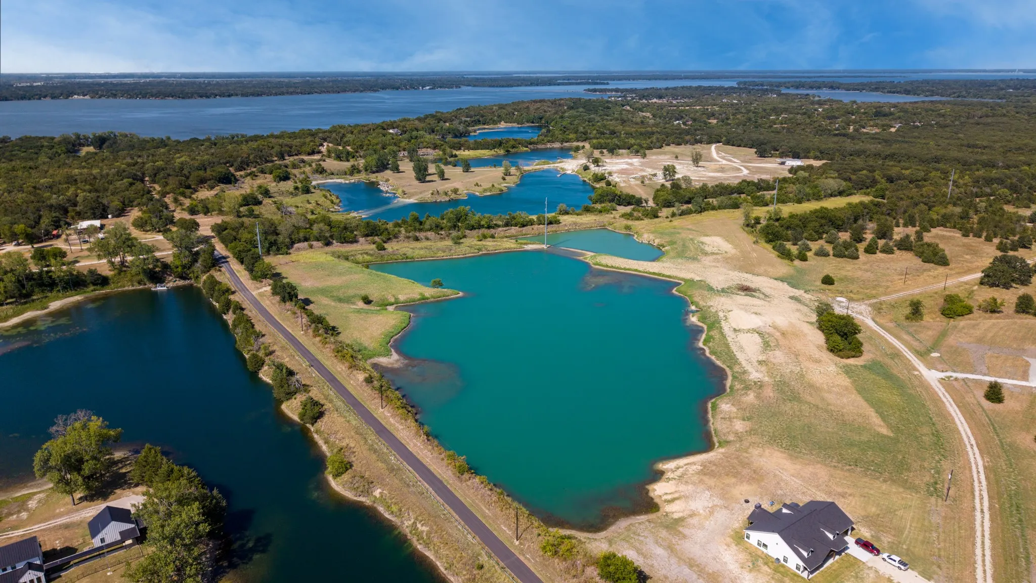 Multiple bodies of water, extensive natural landscaping, surrounding treeline, and paved road access