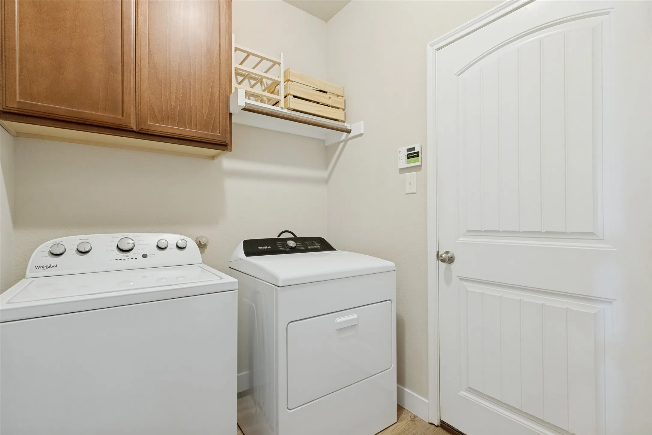 Laundry area with wood-finish cabinetry, a white wall shelf, and a paneled door