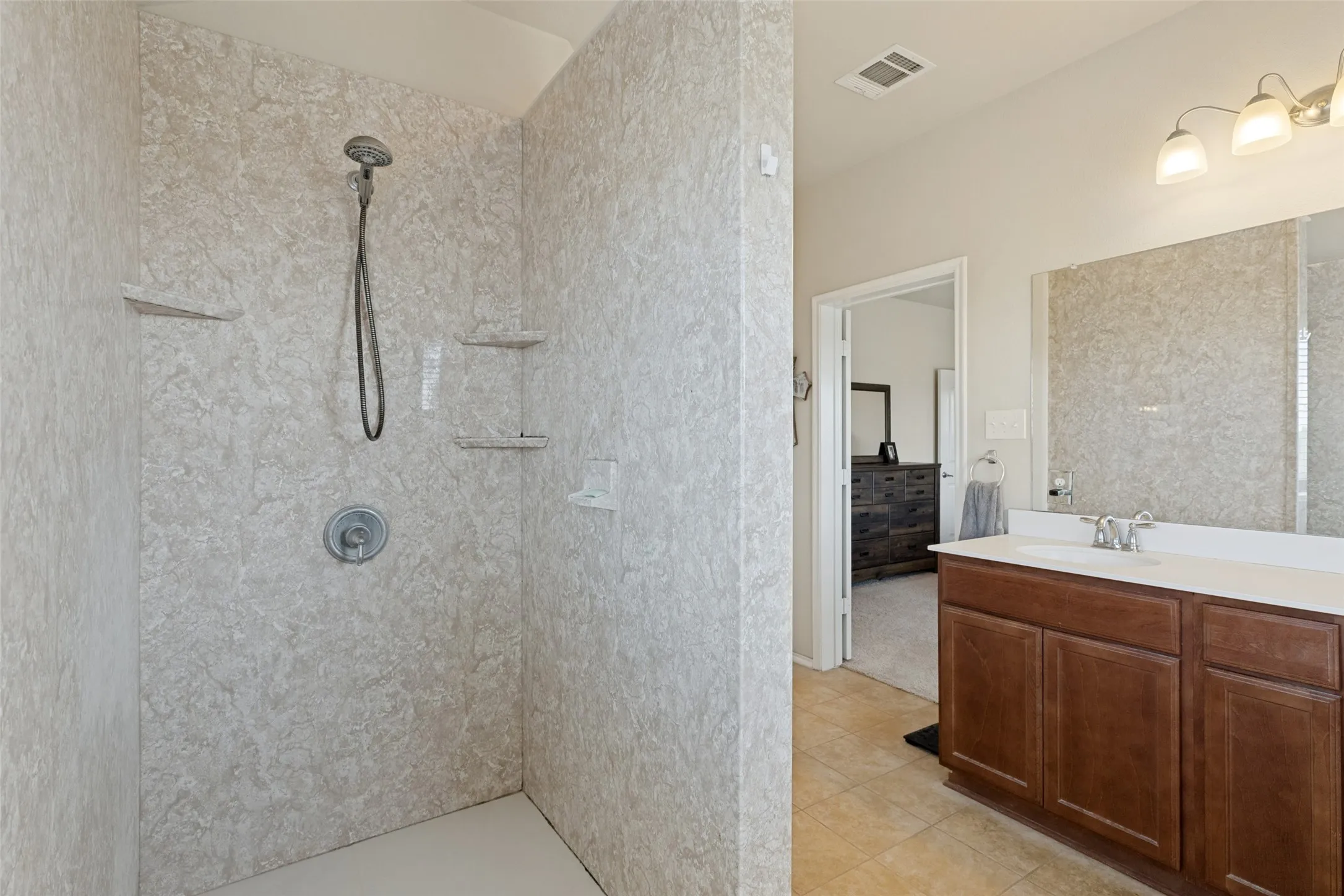 Walk-in shower with textured wall panels and integrated shelving