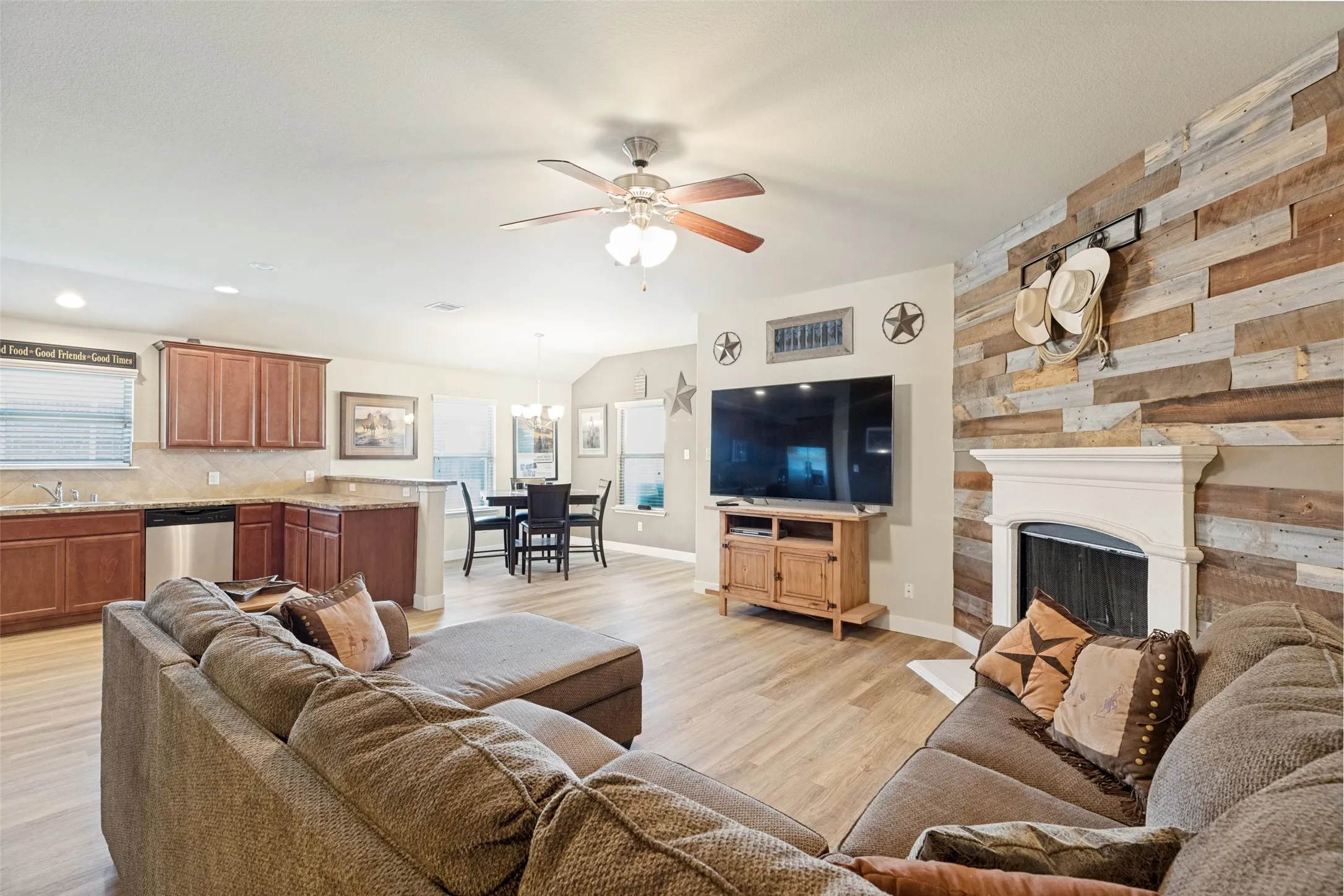 Open-concept living area with wood-finish flooring, a ceiling fan, and a fireplace.