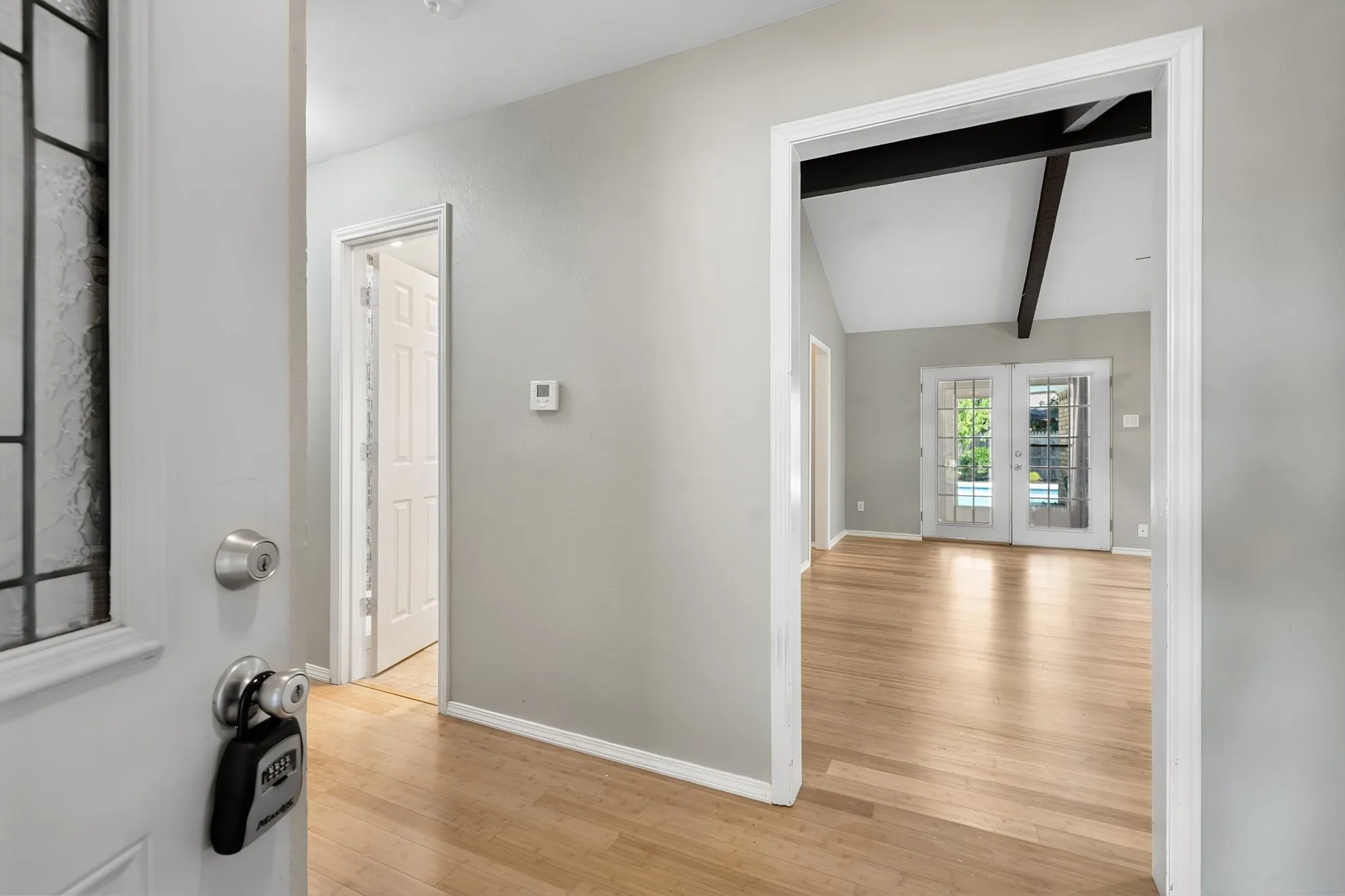 Step inside to bamboo flooring and an inviting view into the spacious living room, with French doors providing a glimpse of the pool beyond.