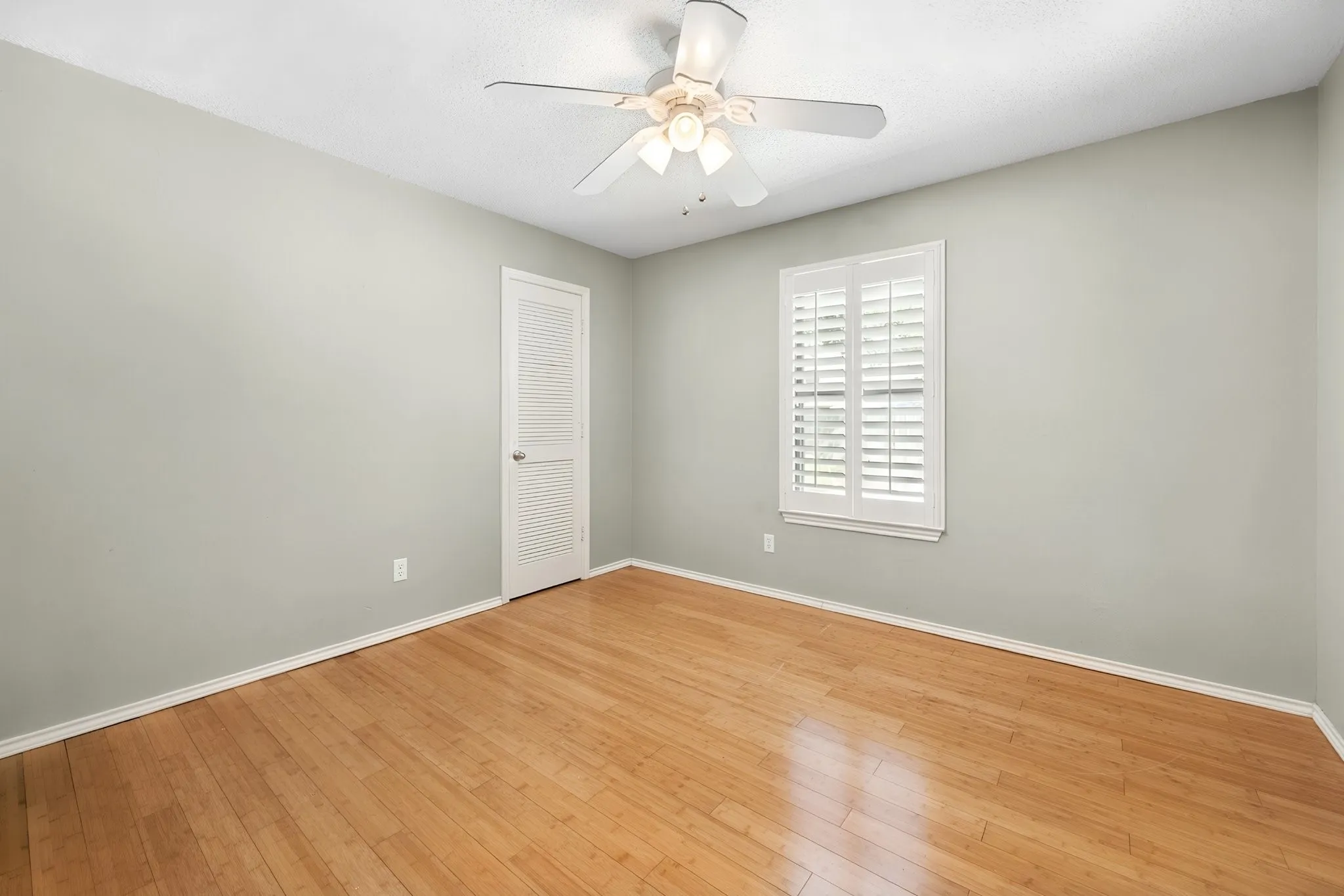 Bamboo flooring and plantation shutters add character to this secondary bedroom, with flexibility for sleeping, working, or creative space.