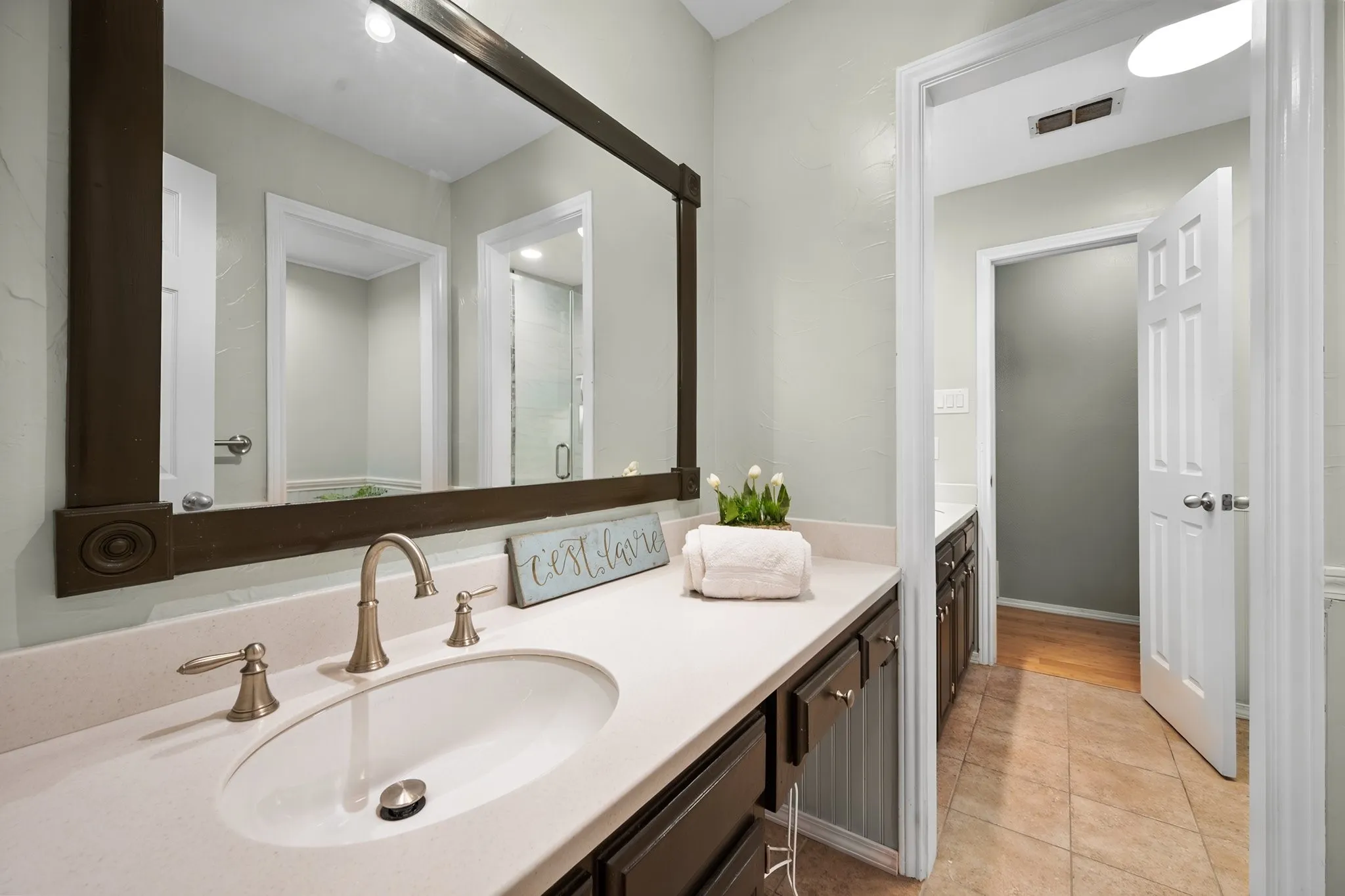 Updated secondary bathroom offers a clean, functional vanity area with convenient storage and counter space.