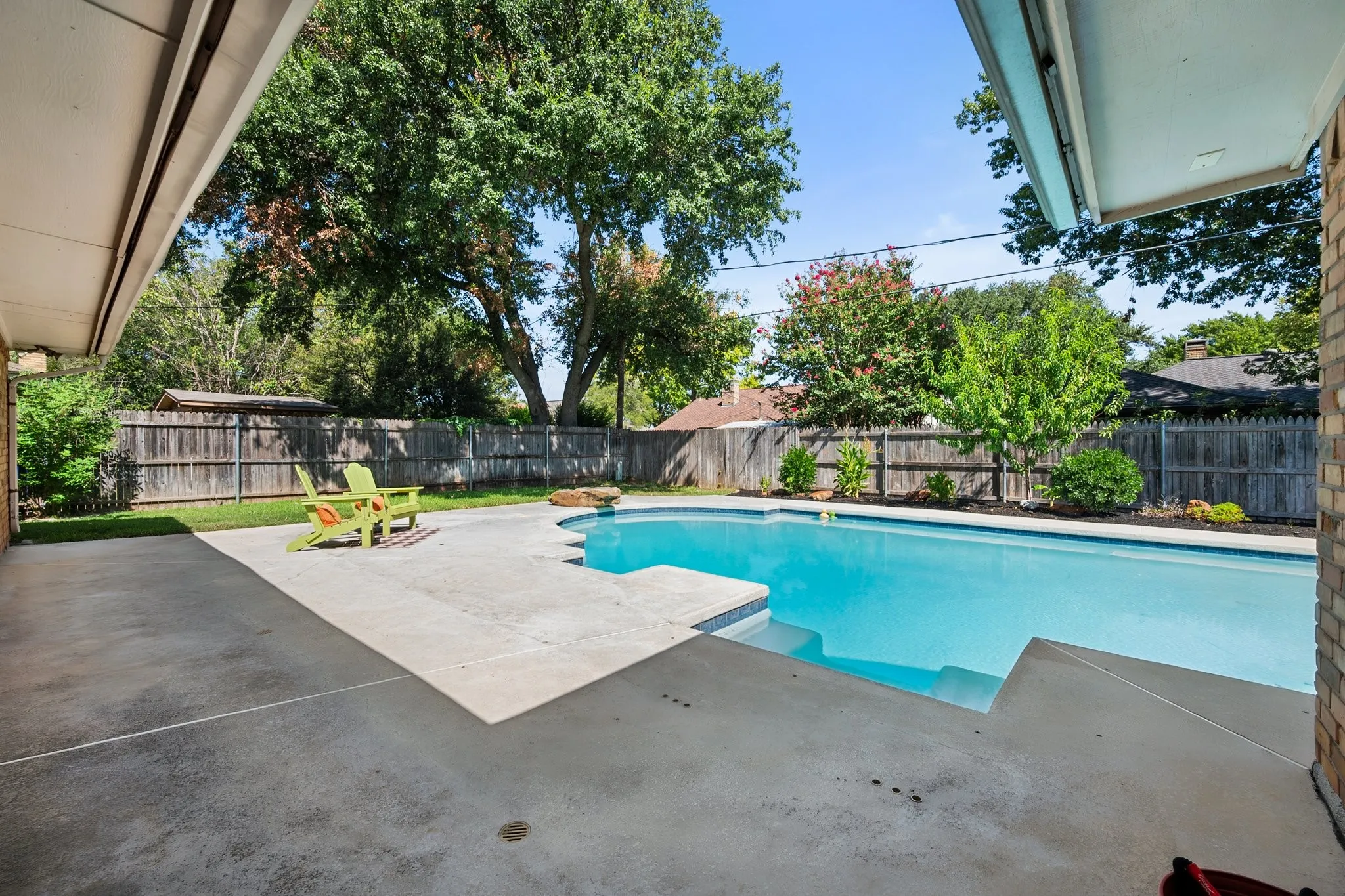 Expansive backyard featuring a large in-ground pool, generous pool decking, mature landscaping, and additional green space for outdoor enjoyment.