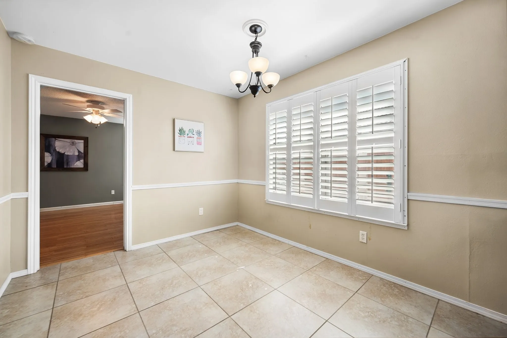 Natural light fills the kitchen and adjoining dining area, with granite countertops, abundant cabinetry, and plantation shutters.