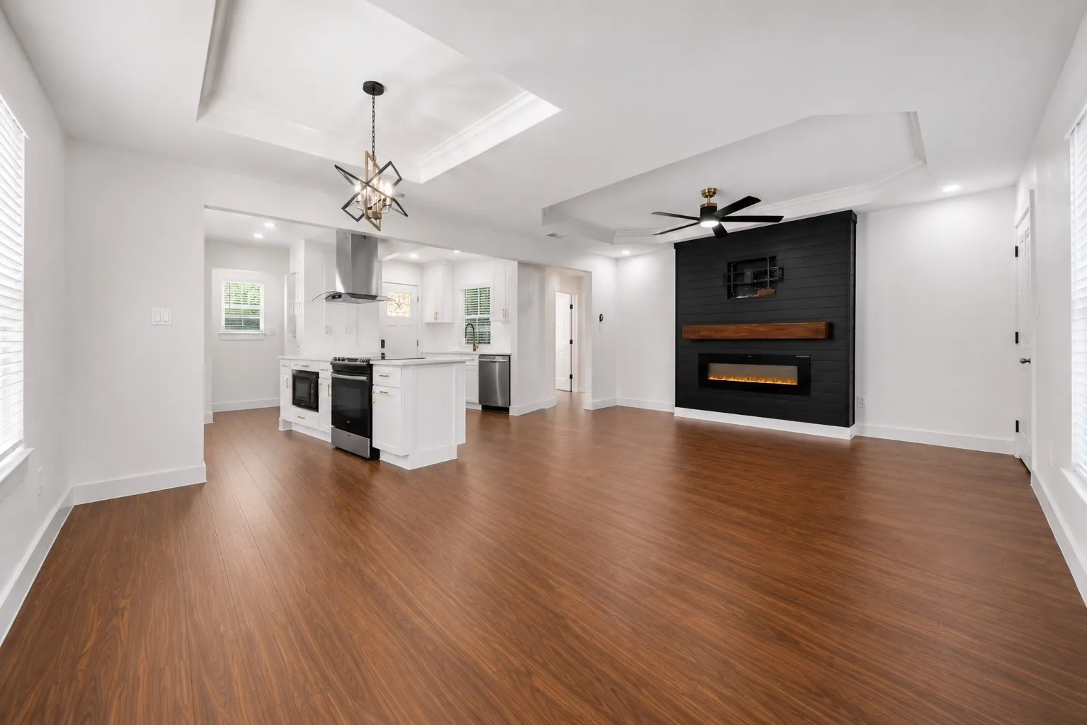 Open-concept living space featuring wood-finish flooring, a contemporary ceiling fan, and a kitchen with stainless steel appliances and a center island