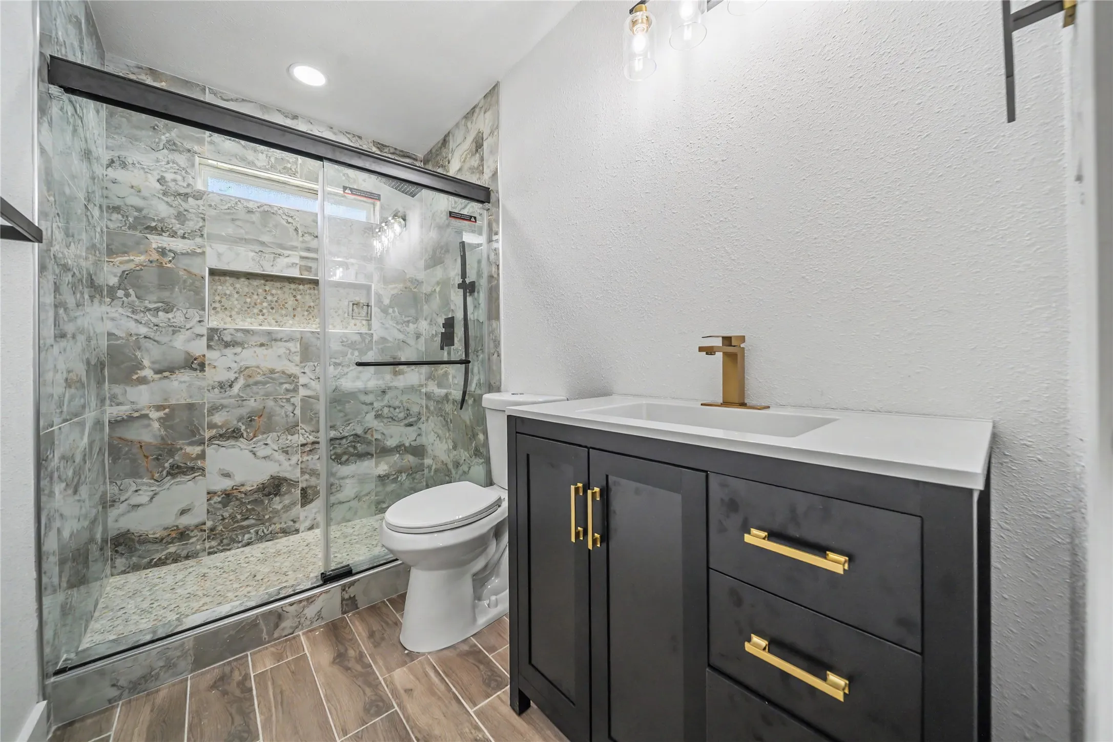 Bathroom featuring a dark wood-finish vanity with gold-tone hardware, a white countertop, and a contemporary gold-tone faucet
