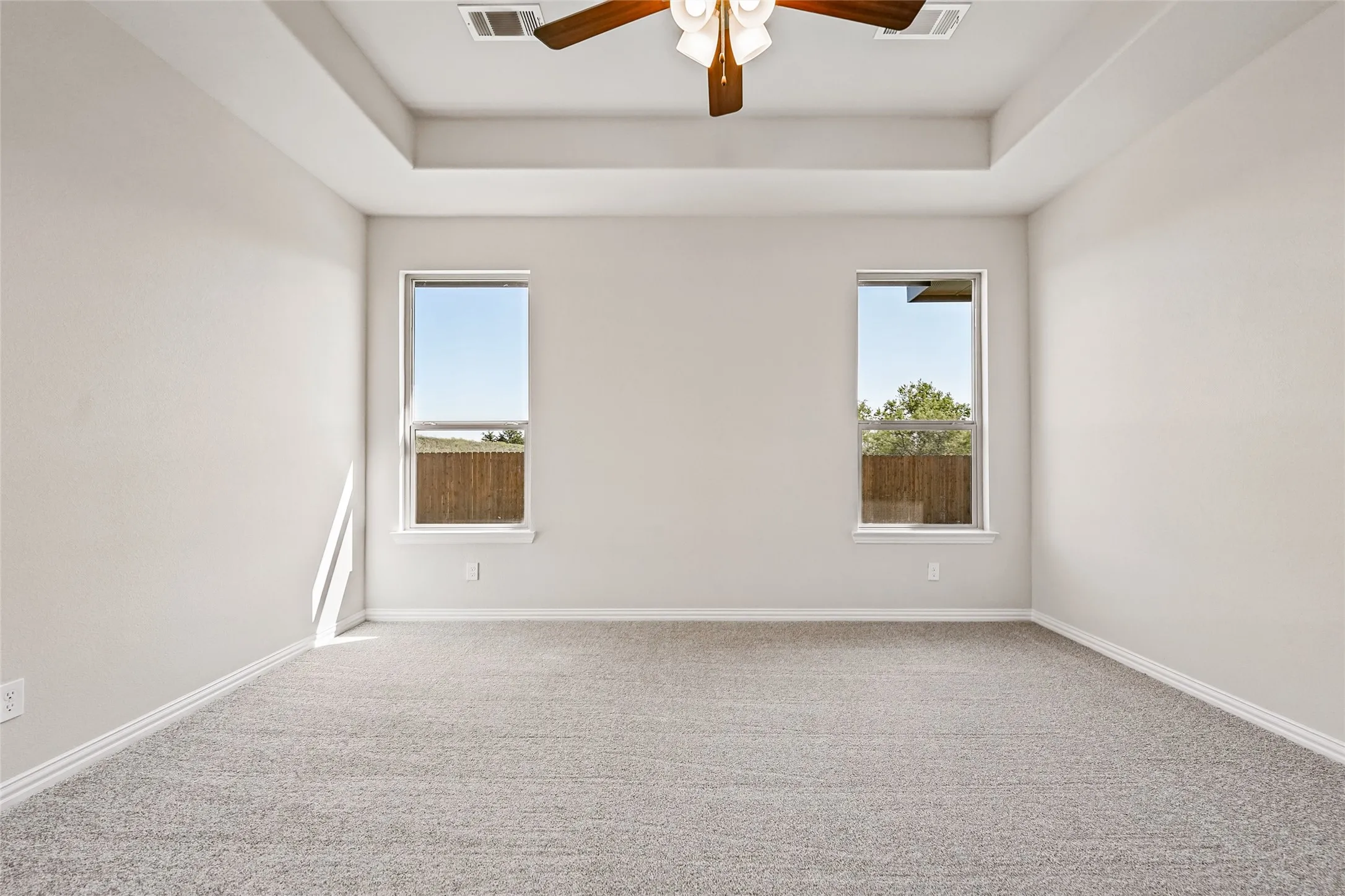 Tray ceiling featuring a ceiling fan with integrated lighting