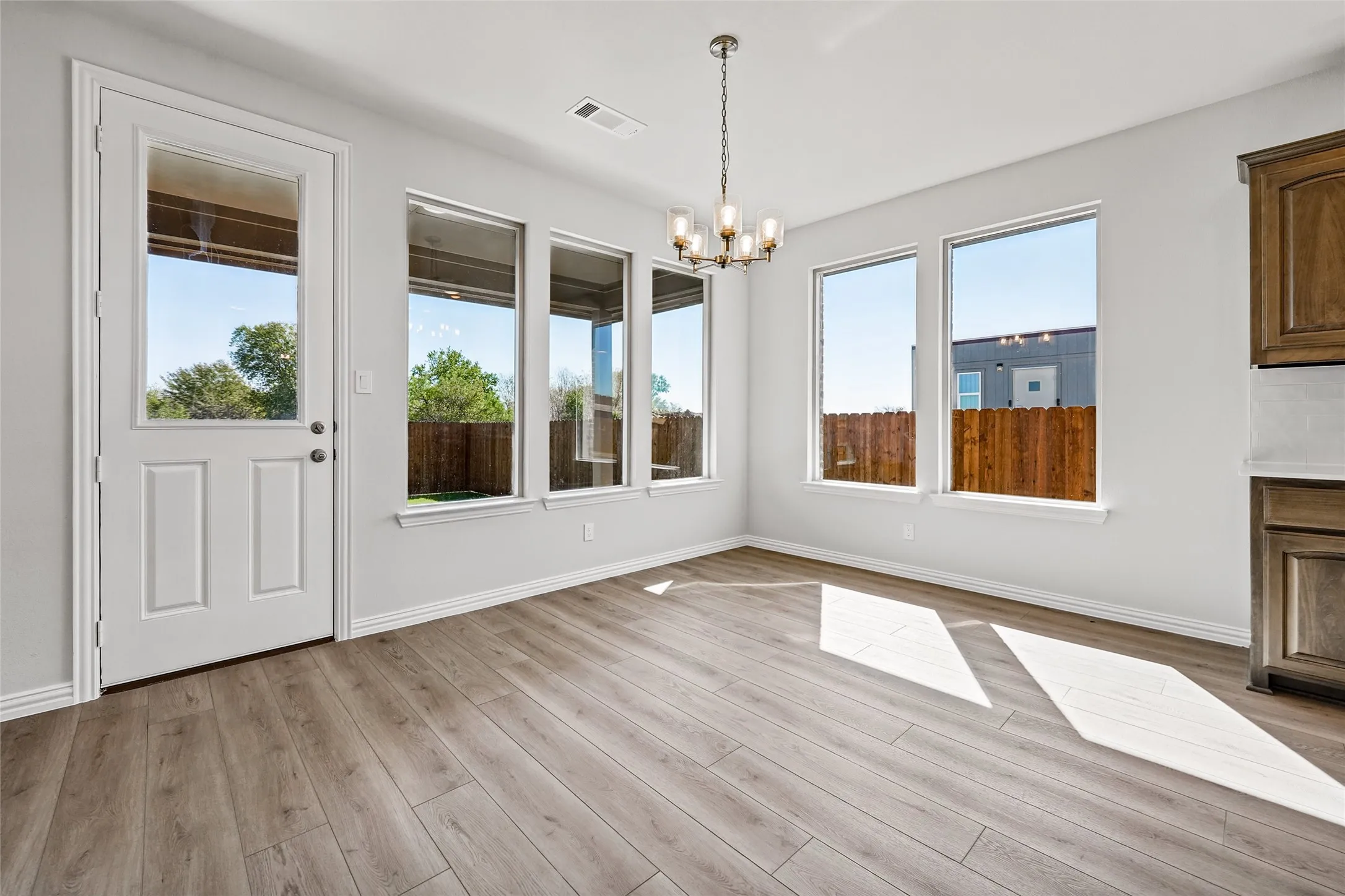 Wood-finish flooring, multiple pane windows, white trim, recessed lighting, and a contemporary chandelier