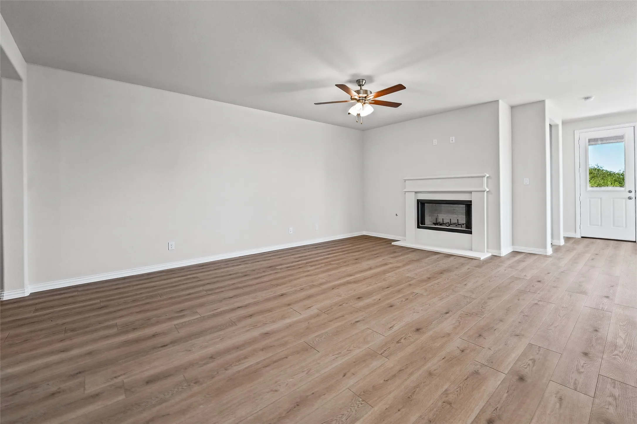 Spacious room featuring wood-finish flooring, a white mantel fireplace, a ceiling fan, and recessed lighting
