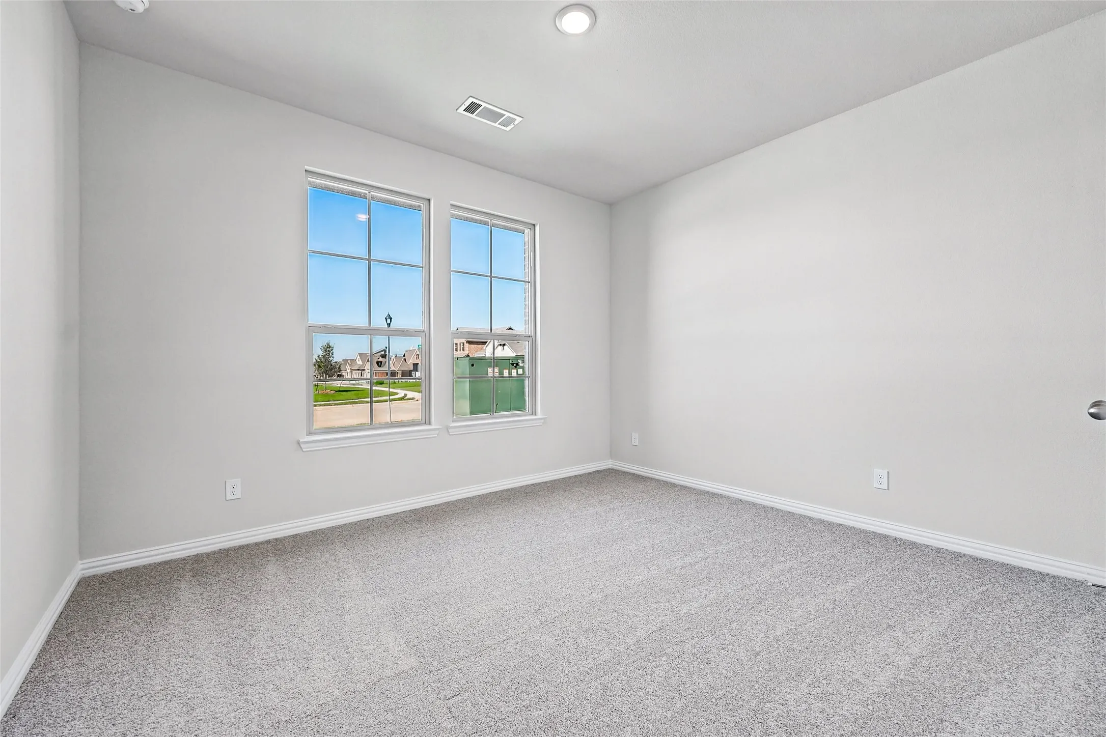 White interior paint, recessed ceiling lighting, light grey carpet, white trim work, and dual windows