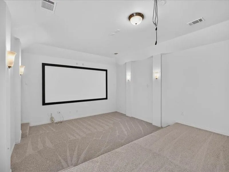Integrated projection screen, wall-mounted sconces, ceiling-mounted light fixture, and carpeted flooring