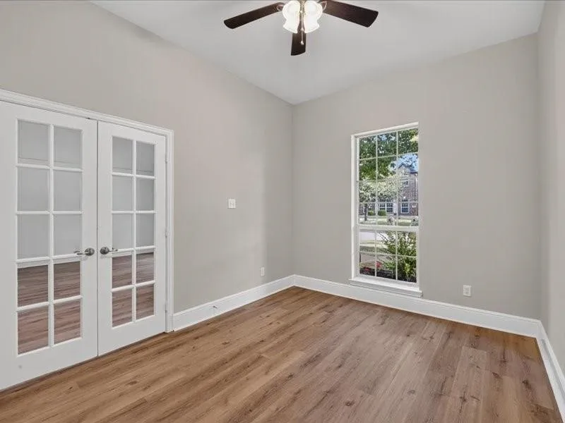 Wood-finish flooring, French doors with divided lites, single-pane window, ceiling fan with light fixture, and vaulted ceiling