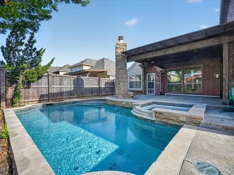 Backyard oasis featuring a swimming pool, integrated spa, and expansive patio area