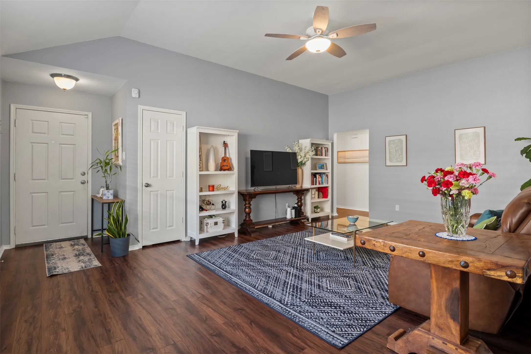 Vaulted ceilings, wood-finish flooring, ceiling fan with integrated lighting, and paneled interior doors