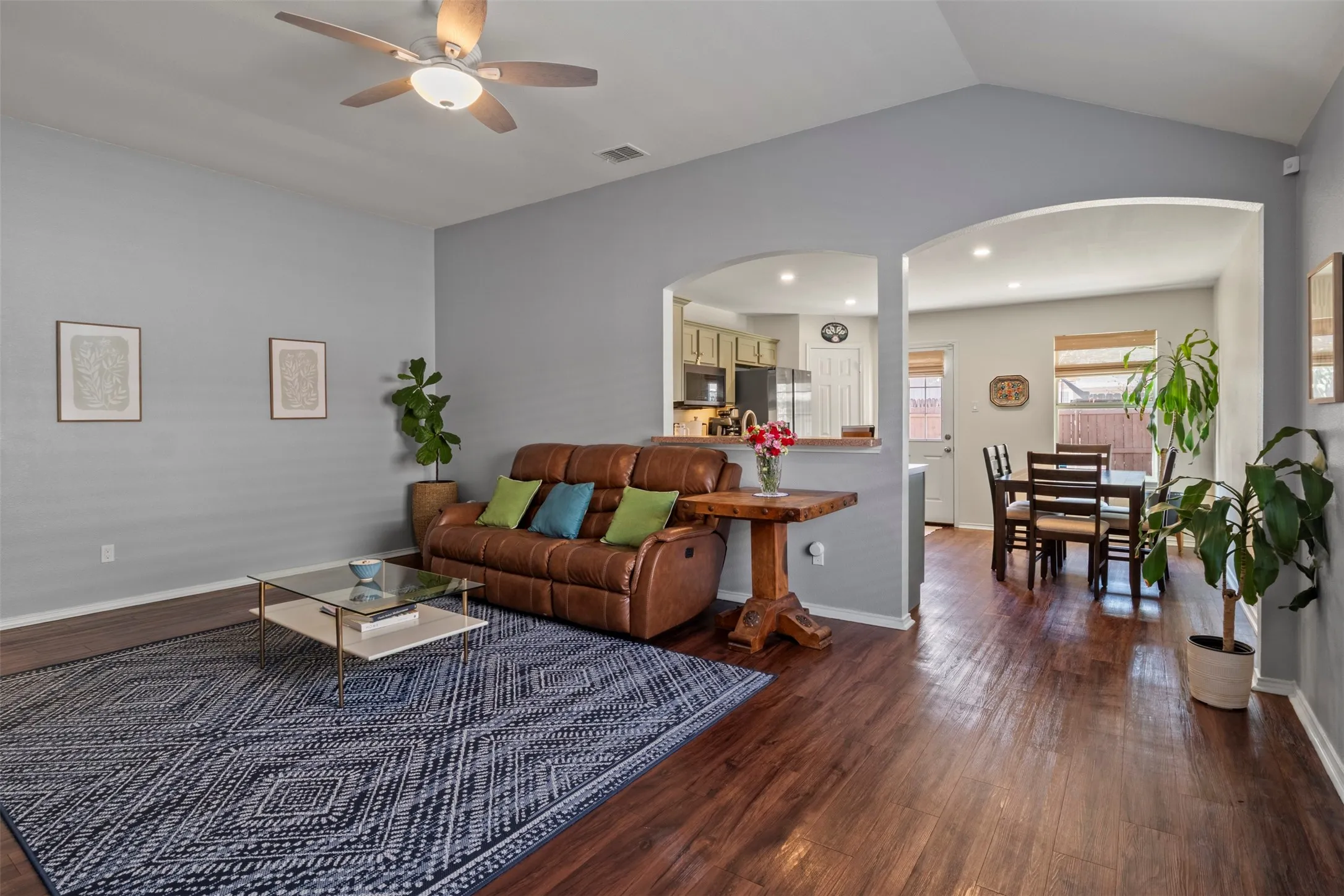 Vaulted ceilings, wood-finish flooring, arched doorways, ceiling fan with integrated lighting, and recessed lighting