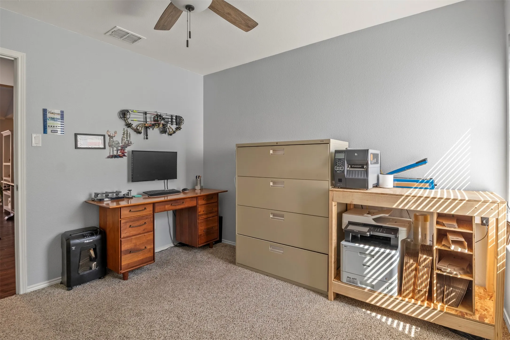 Carpeted room with a ceiling fan, light gray wall finish, and natural light from a window