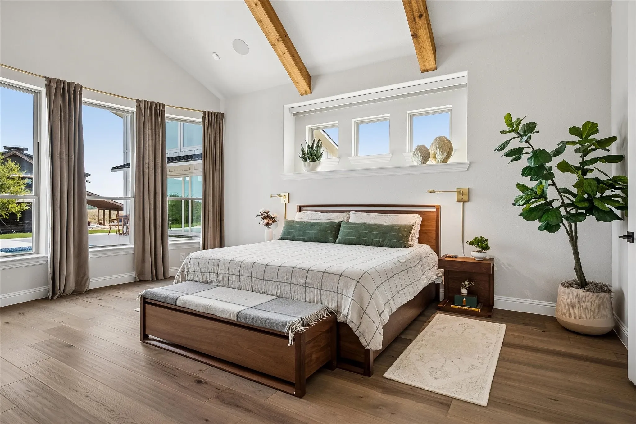 Vaulted ceiling with wooden beams, bay window overlooking pool and pool deck.