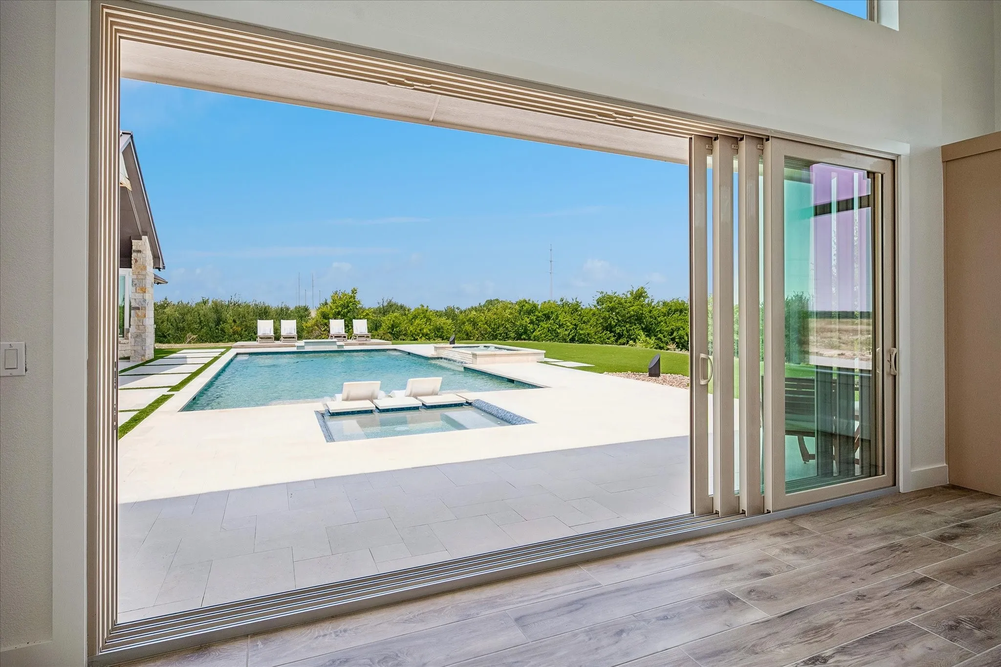 View of the pool area from inside the pool house with the sliding doors open.