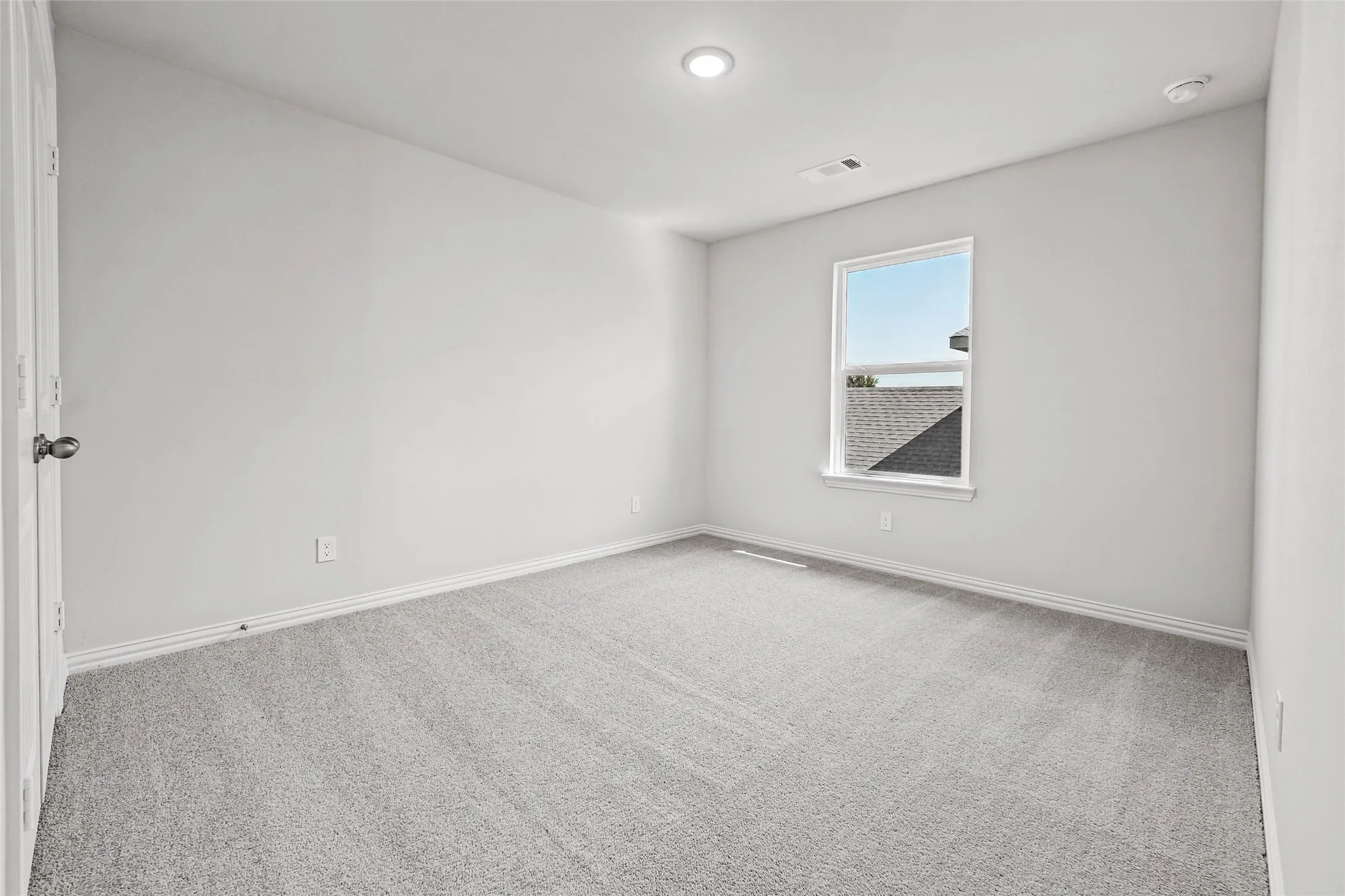 Window with natural light, recessed ceiling lighting, light gray wall paint, gray carpet flooring, and white trim