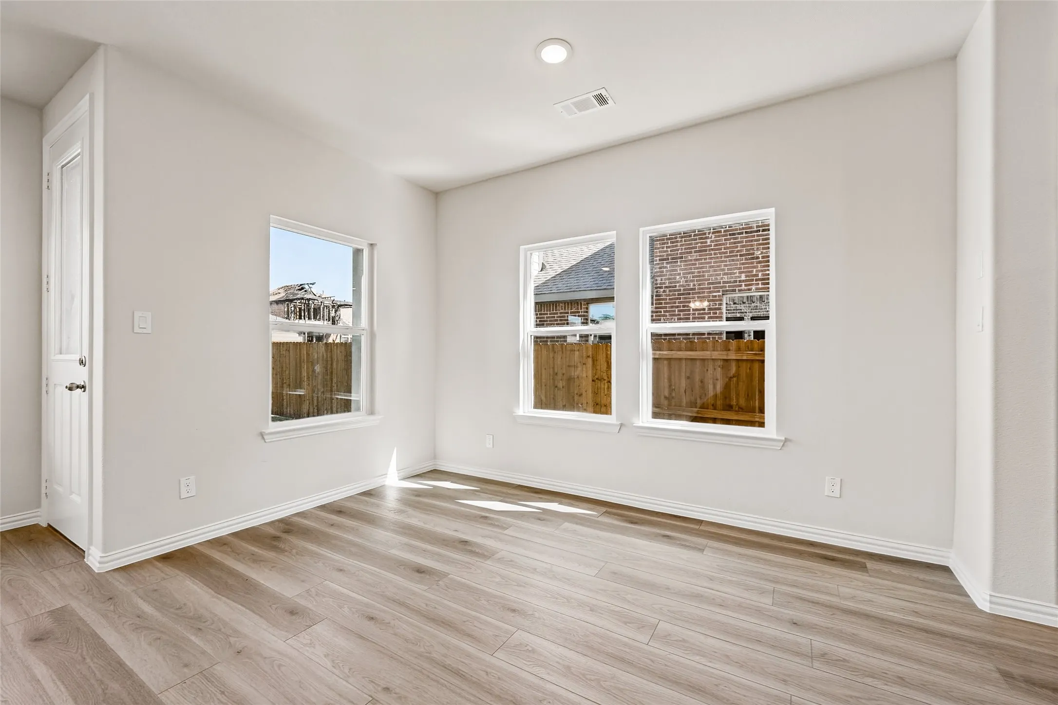 Wood-finish flooring, white walls, and multiple windows with white trim