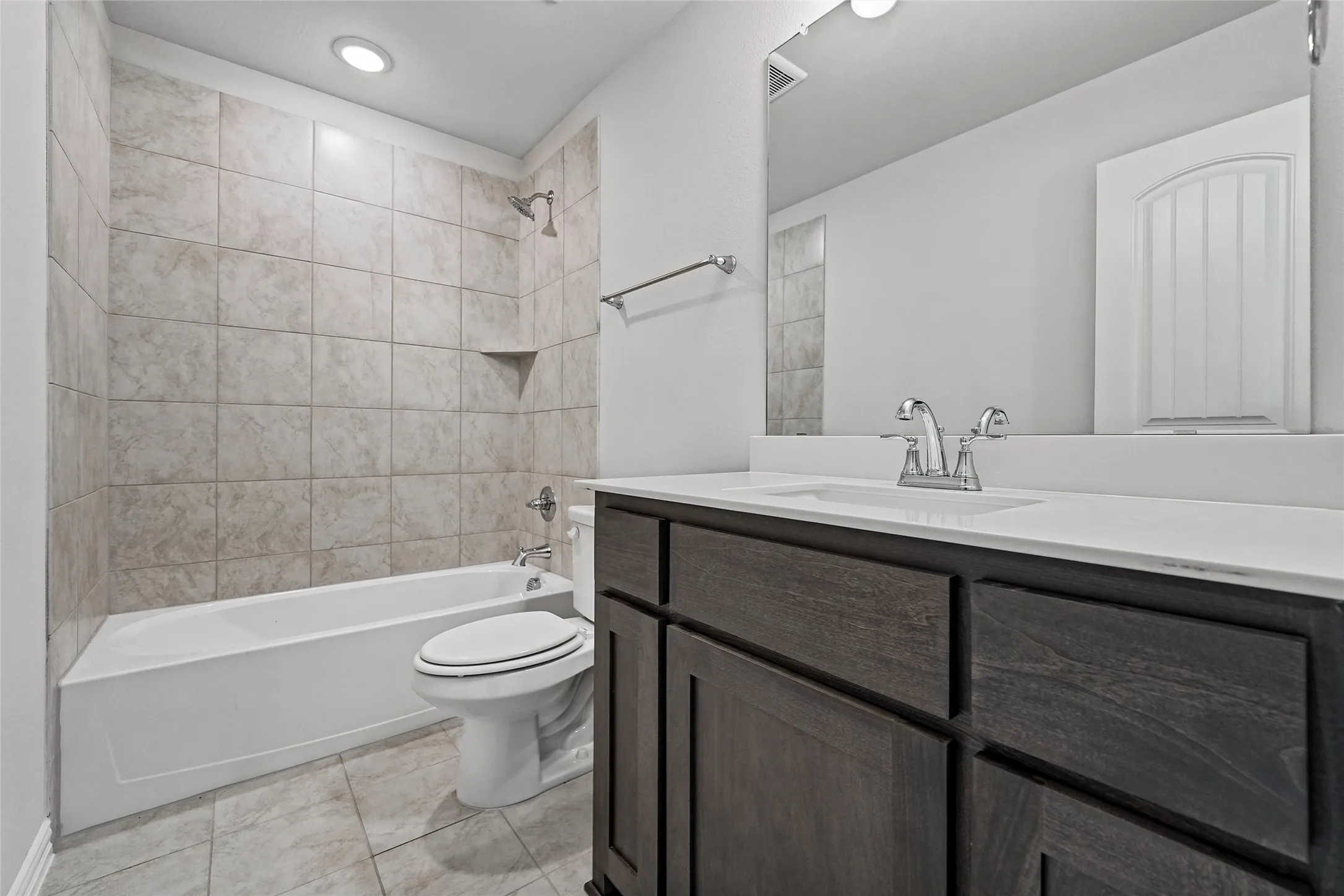 Bathroom featuring a single vanity with dark wood-finish cabinetry, white countertop, and a large wall-mounted mirror