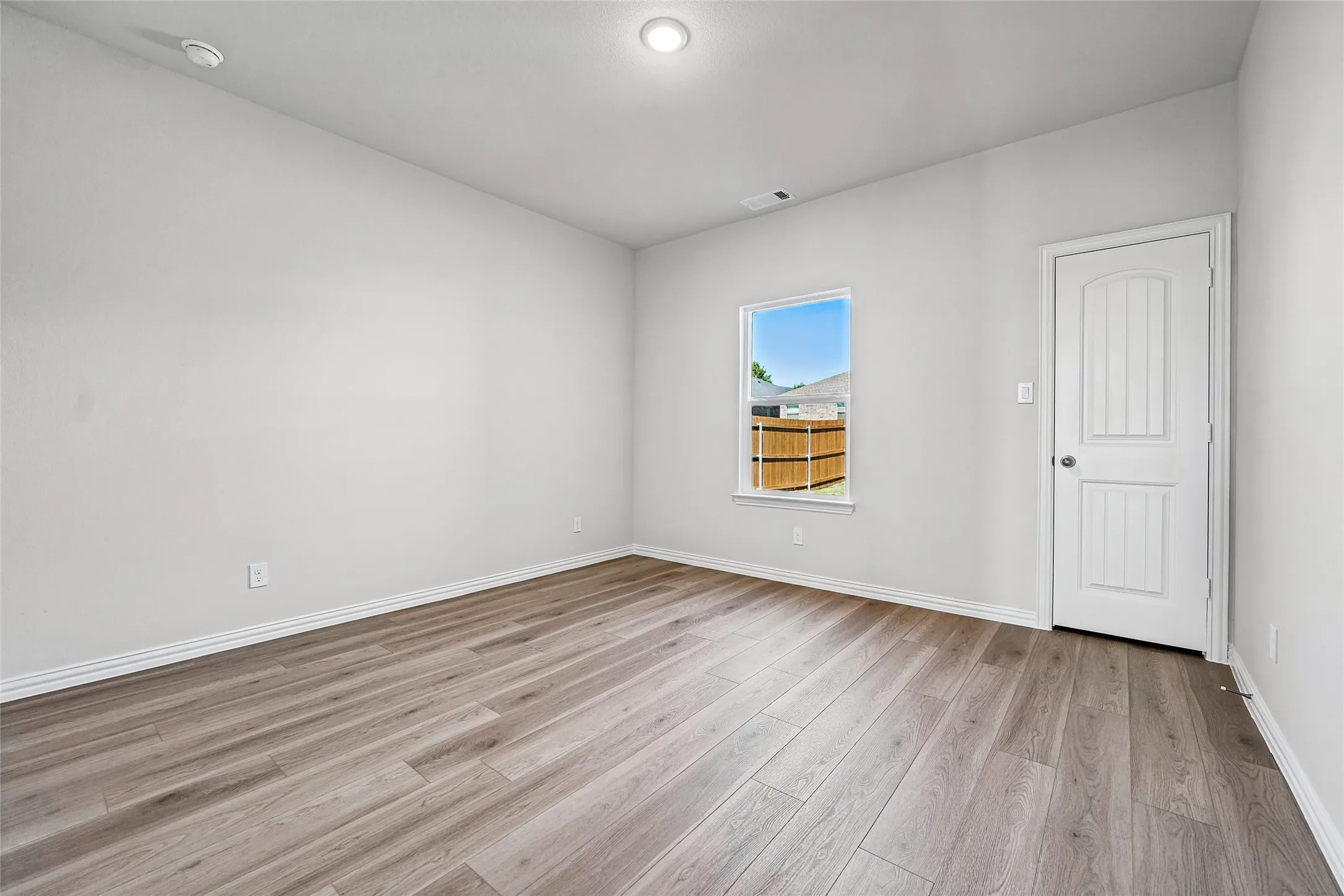 Recessed lighting, wood-finish flooring, and white paneled door