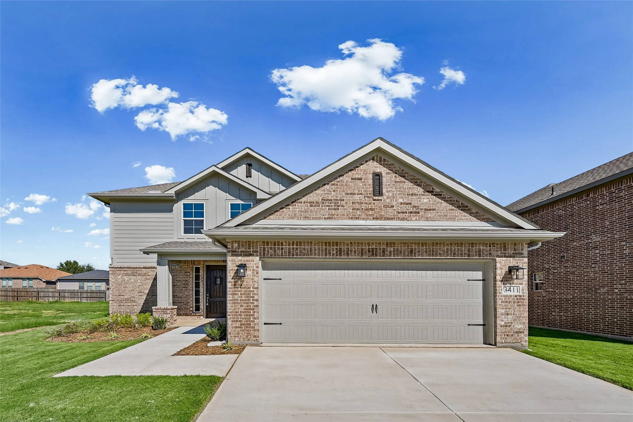 Brick and siding exterior, attached garage, covered entryway, concrete driveway, and a concrete walkway