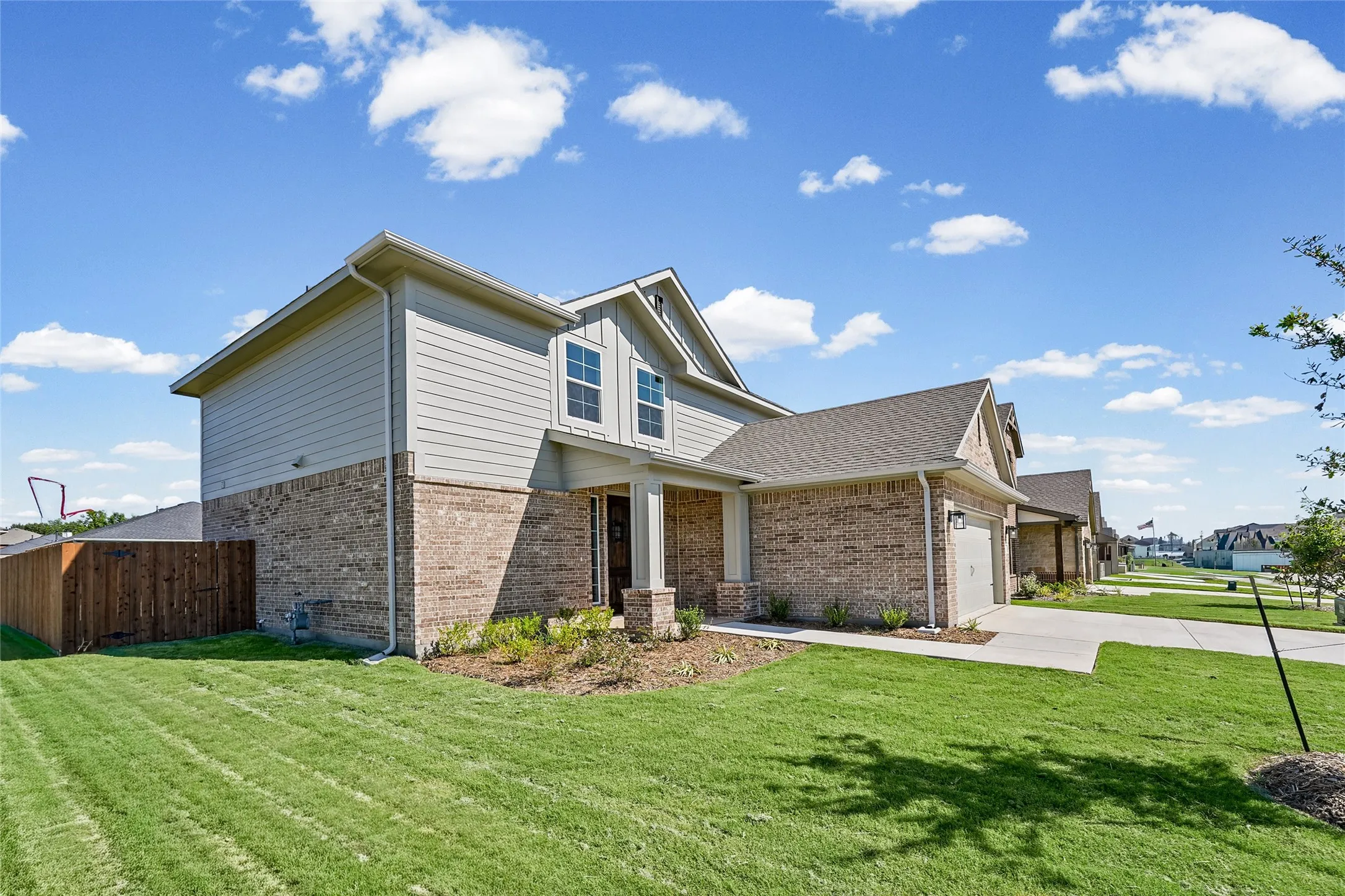 Brick and siding exterior with a covered entry, two-car garage, and a fenced side yard
