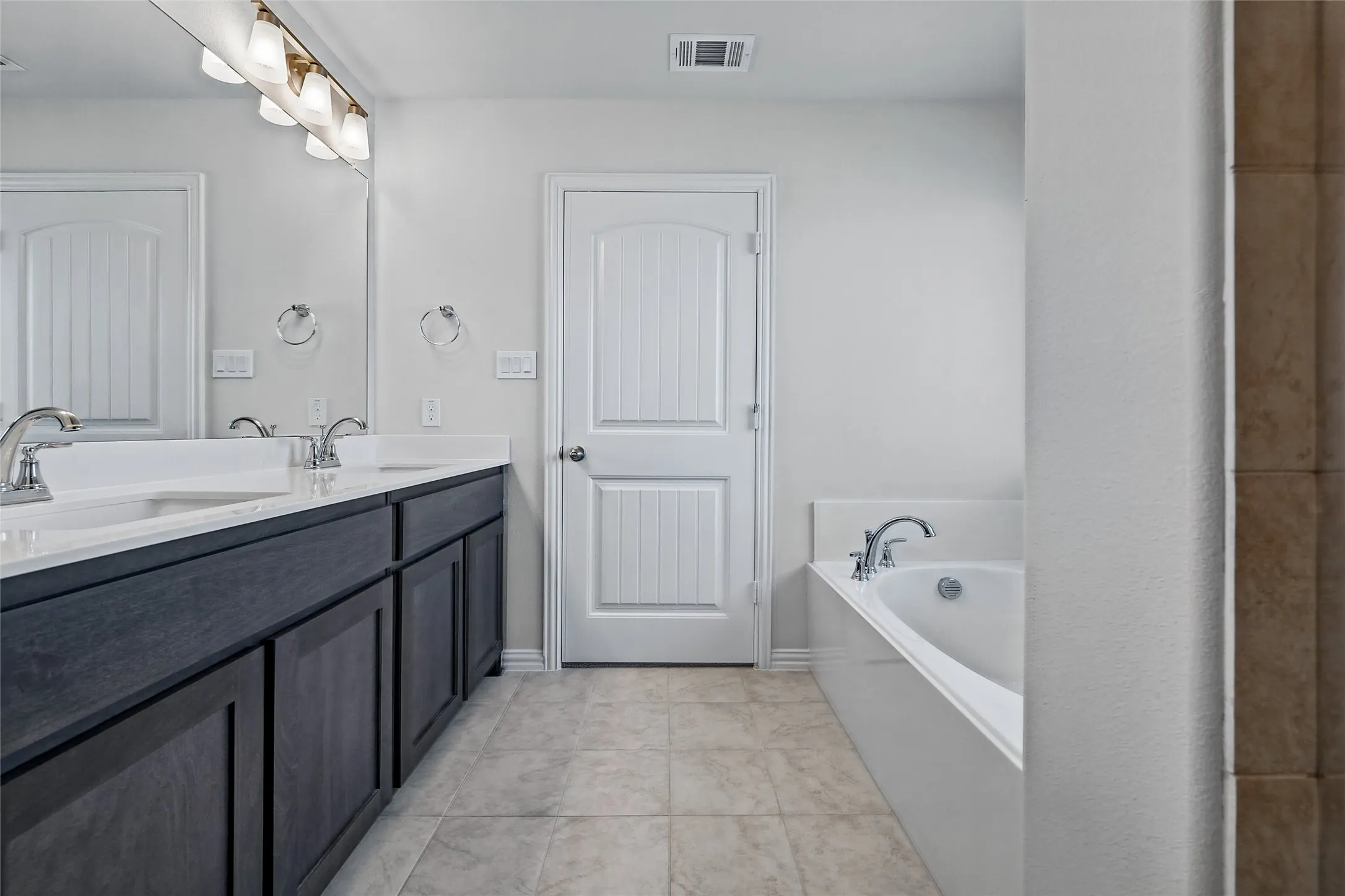 Dual sink vanity with dark wood-finish cabinetry and white countertops