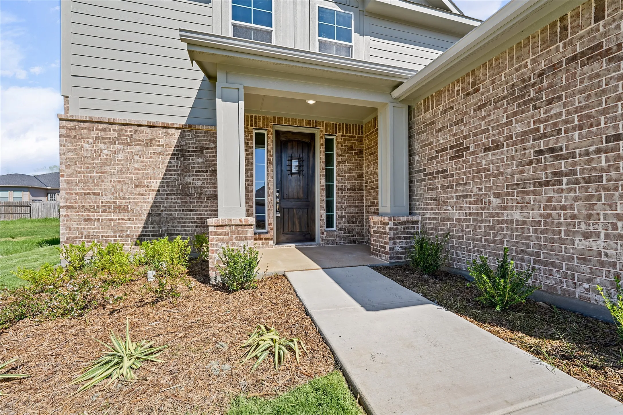 Brick and siding exterior with a covered porch entry