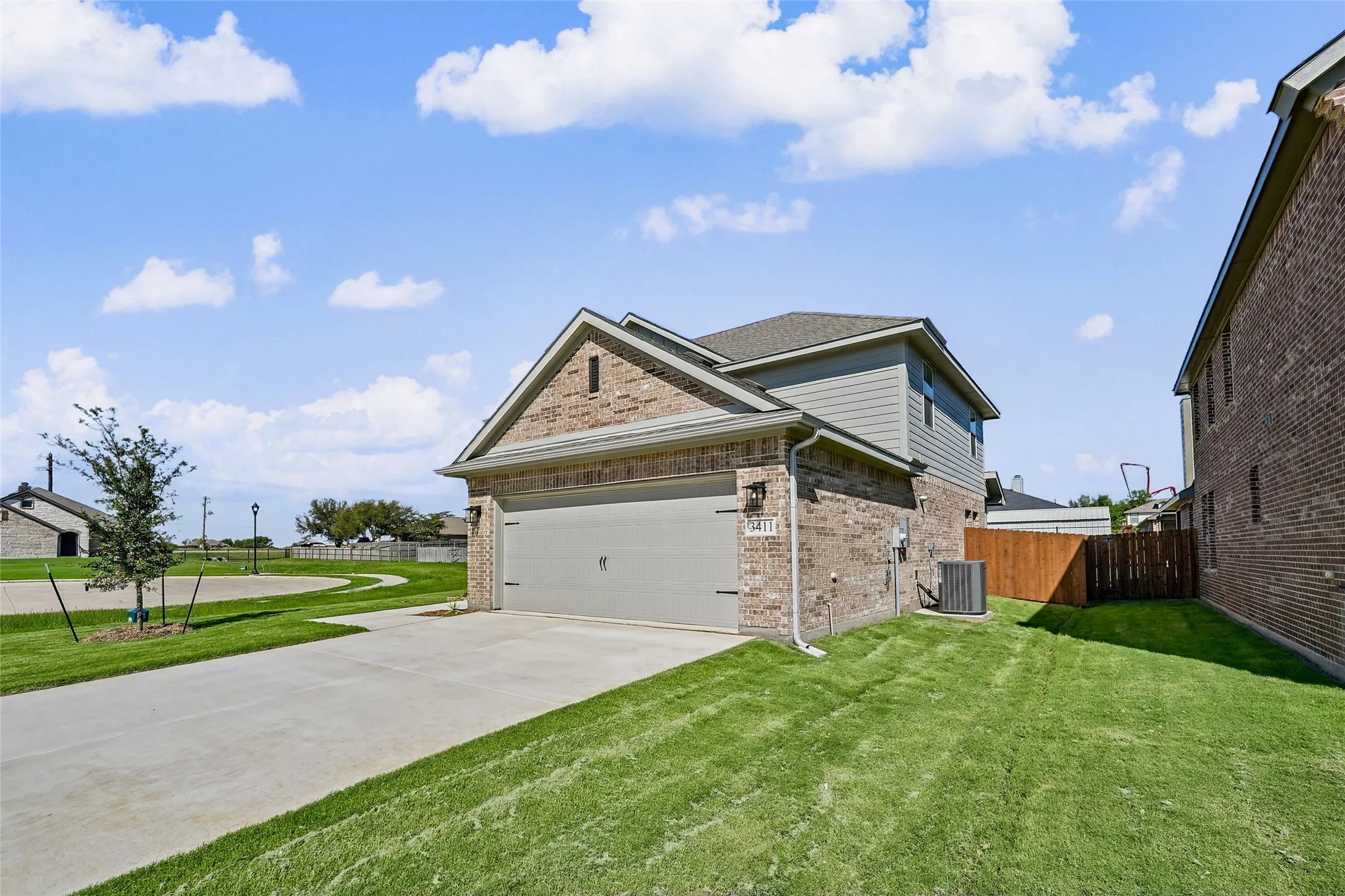 Brick and siding exterior with an attached garage, concrete driveway, and a manicured lawn
