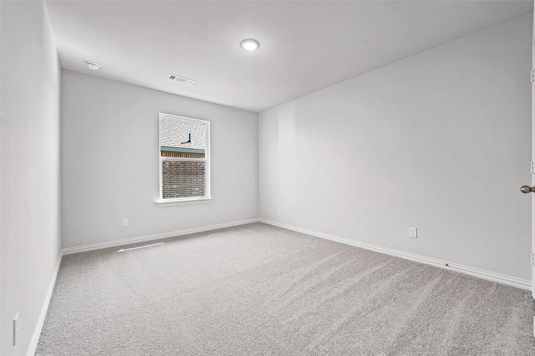 Bright secondary bedroom featuring neutral wall finishes, recessed ceiling lighting, casement window with natural light, and neutral-tone carpeting throughout