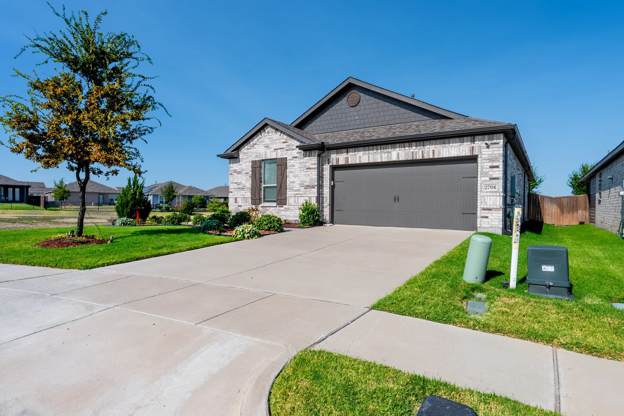Single-story residence featuring a brick and shingle facade, an attached garage, and a concrete driveway