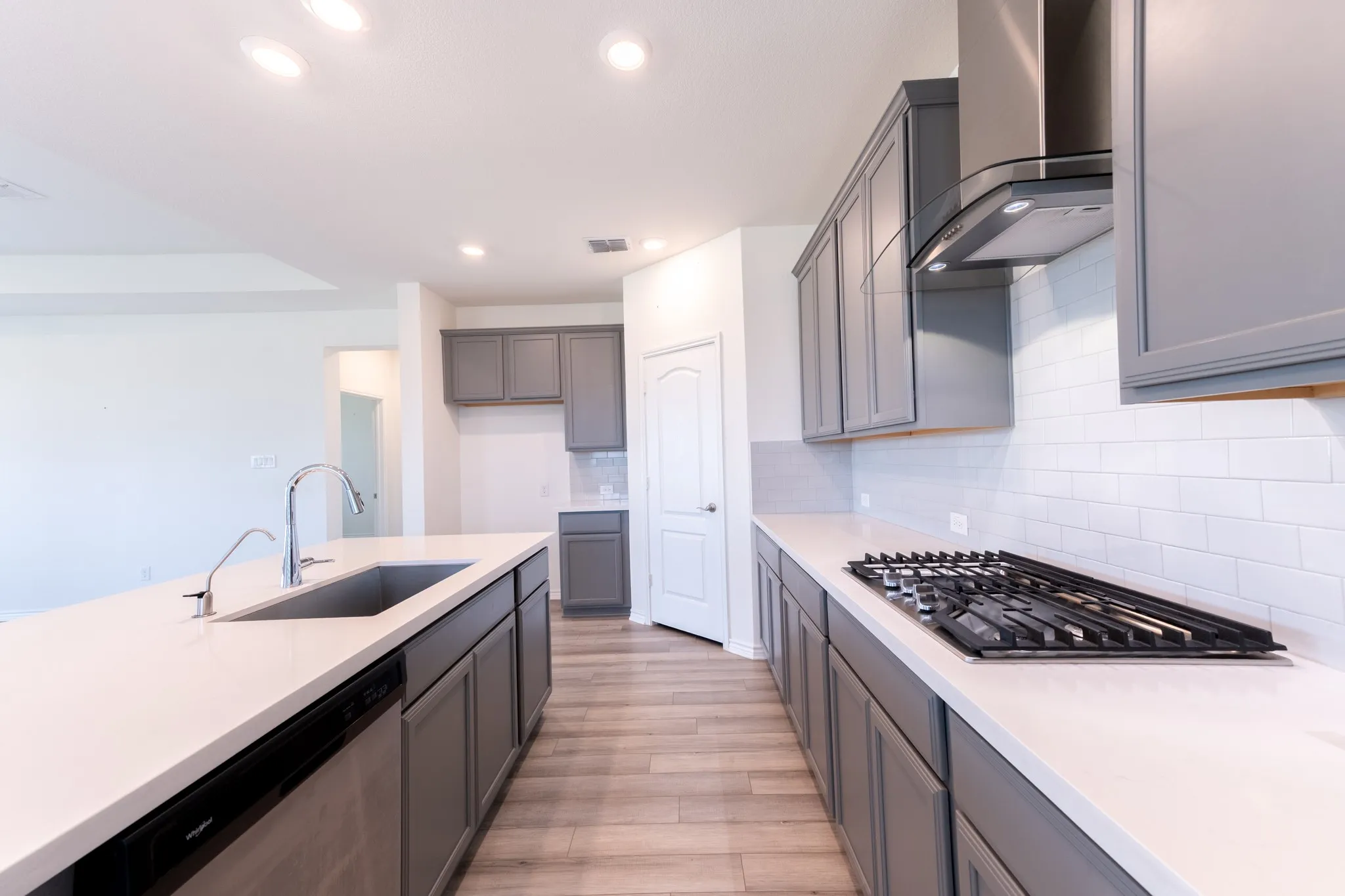 Kitchen featuring a gas range, stainless steel range hood, subway tile backsplash, white quartz countertops